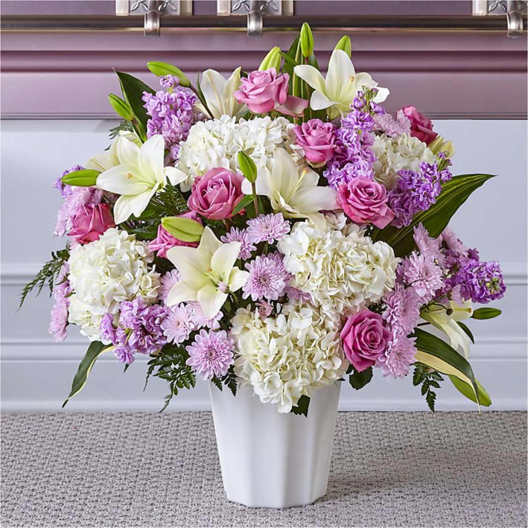 Pink roses, white lilies, and hydrangeas in a white vase