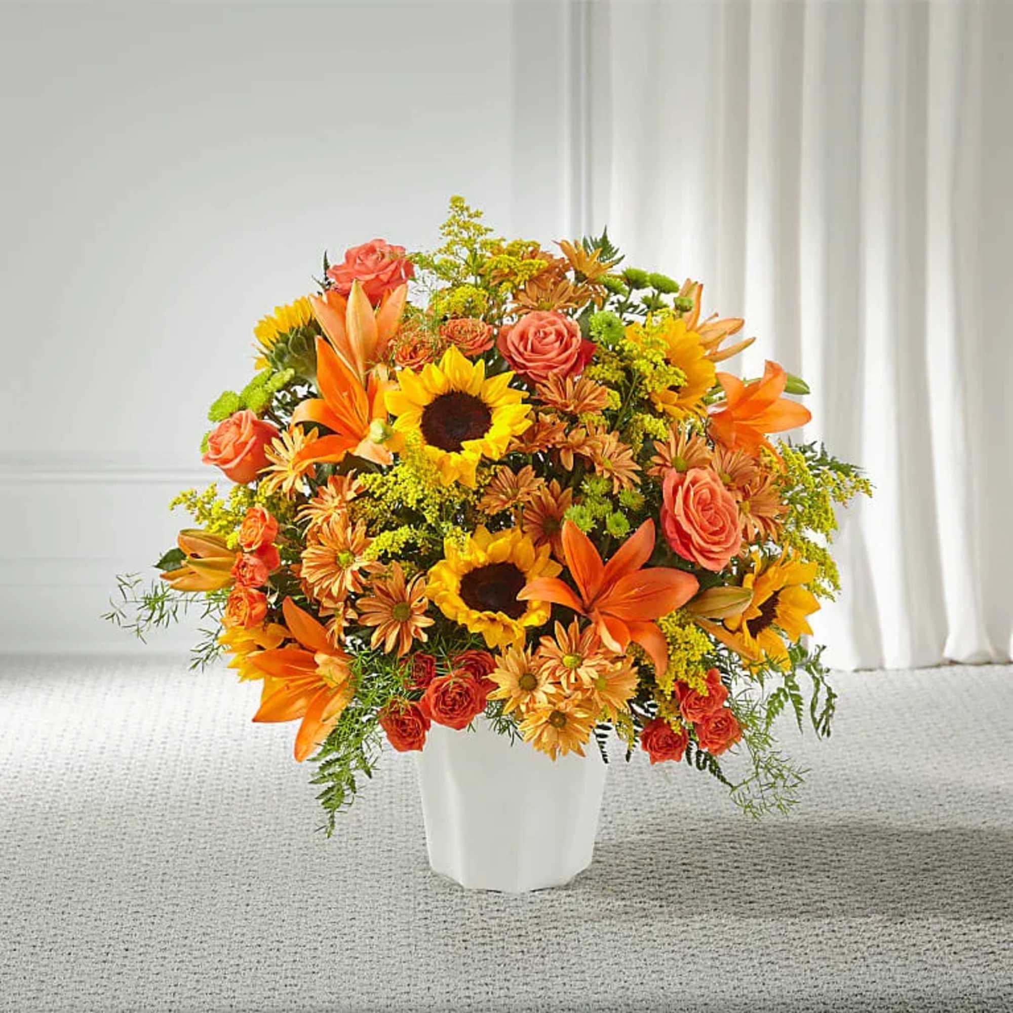 Orange and yellow mixed flower arrangement in a white vase