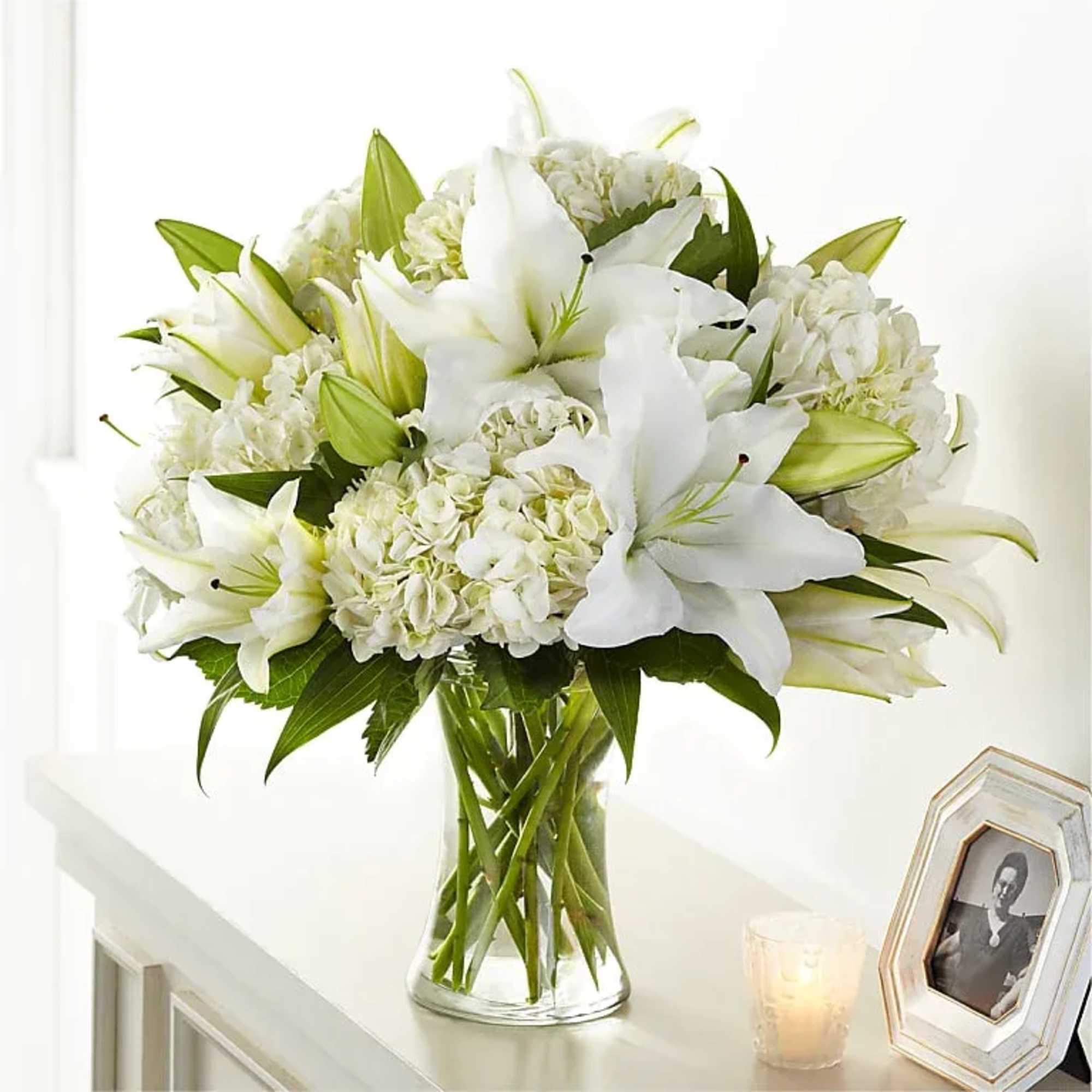 White lilies and hydrangeas arranged in a clear glass vase