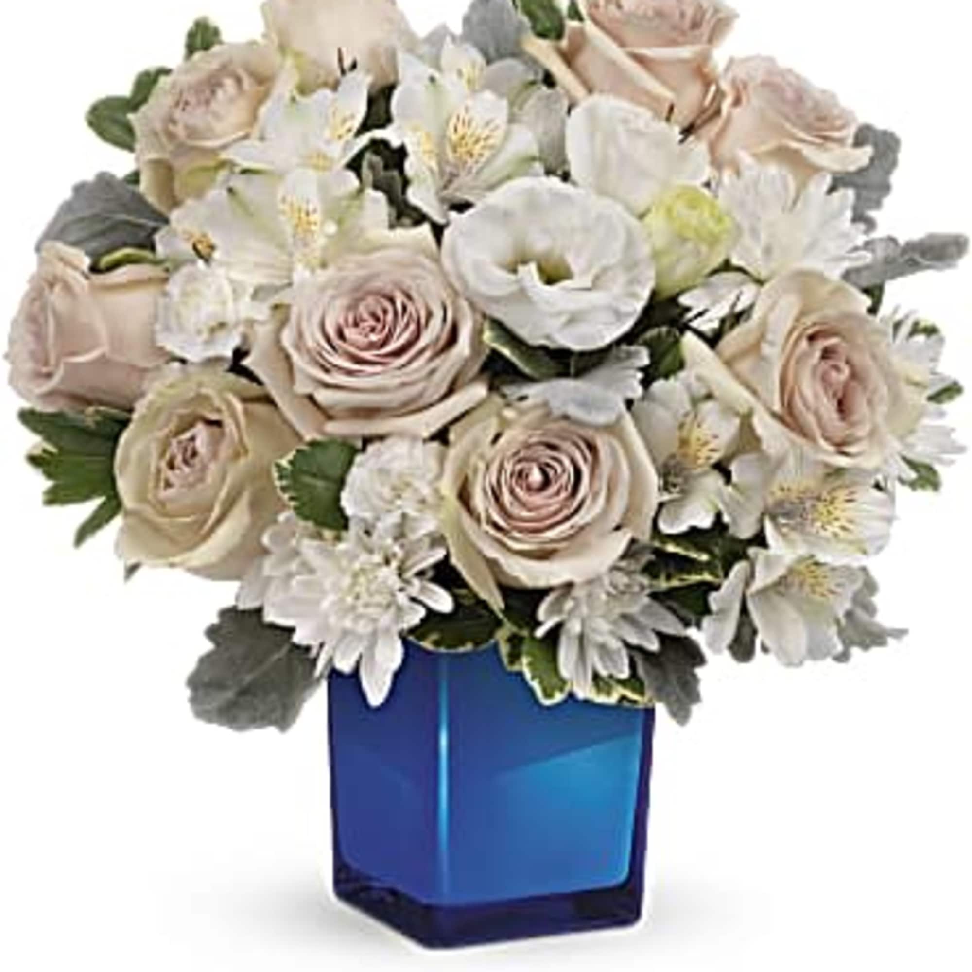 Bouquet of pale roses and white flowers in a blue glass vase