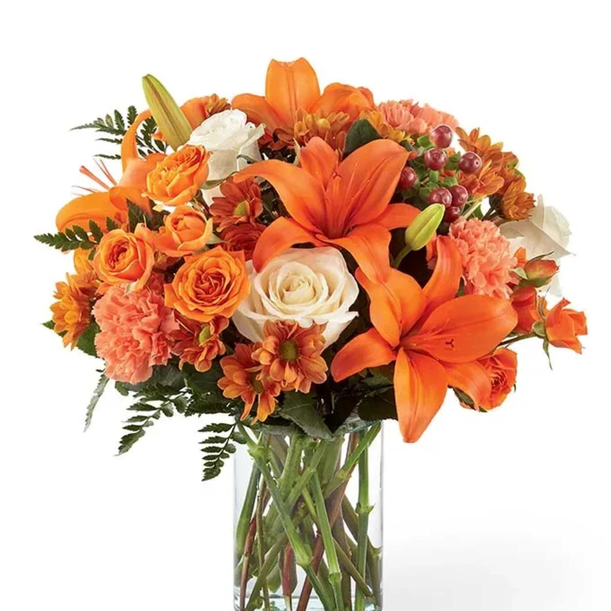 Orange lilies and roses arranged in a clear glass vase
