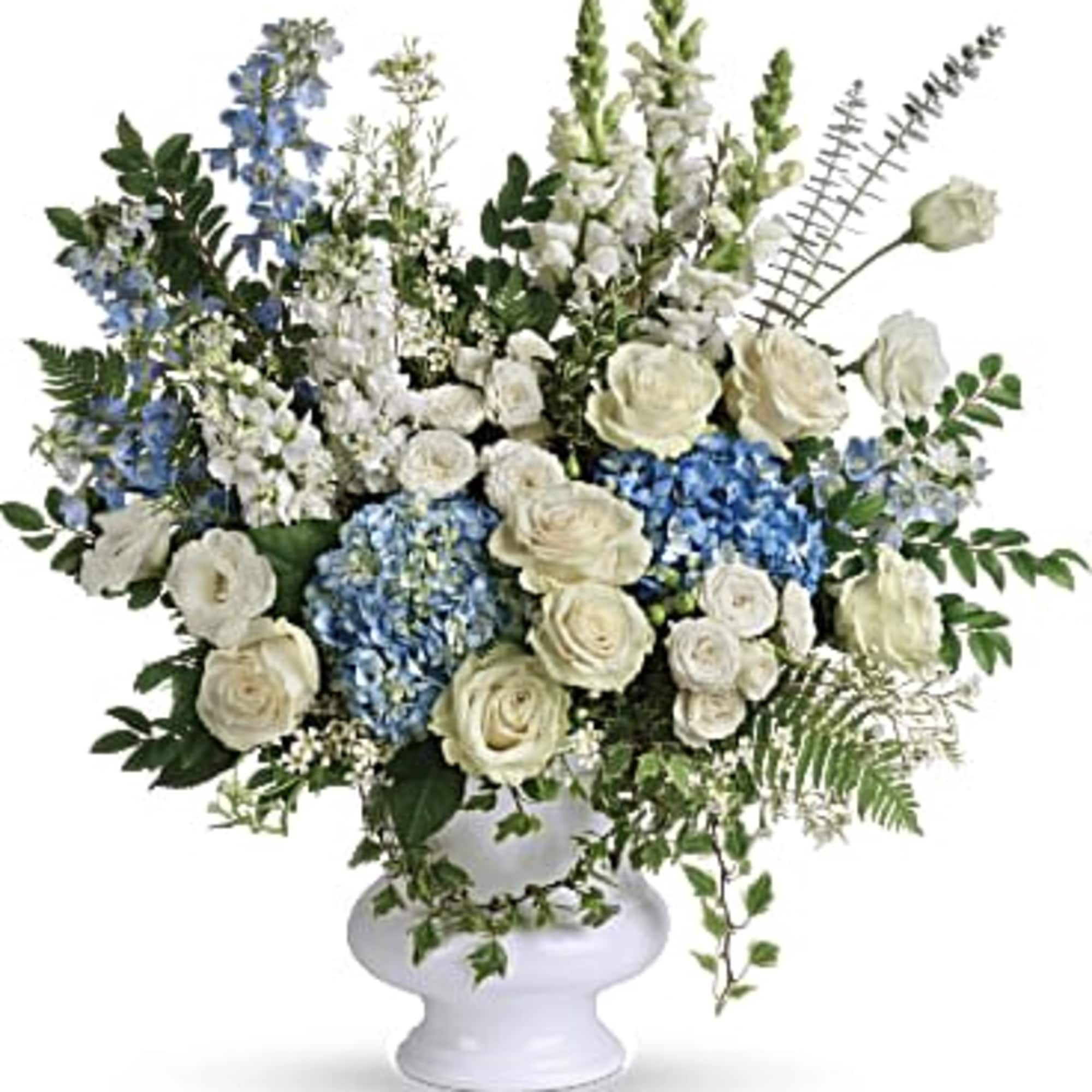 White and blue floral arrangement in a white pedestal vase