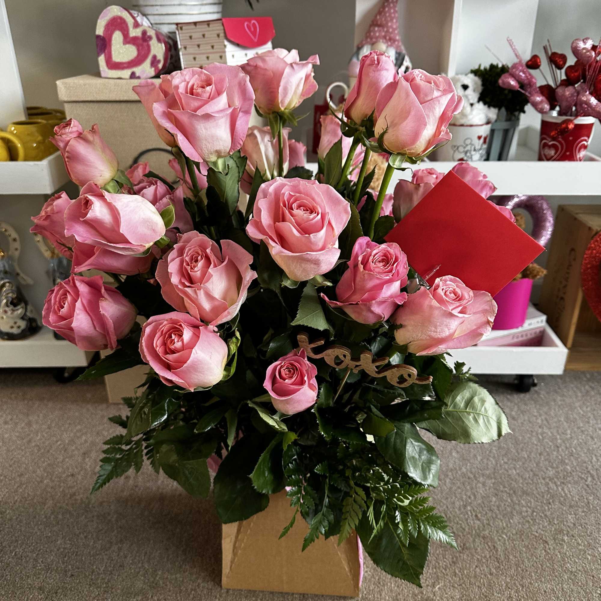 Pink roses arranged in a box with greenery