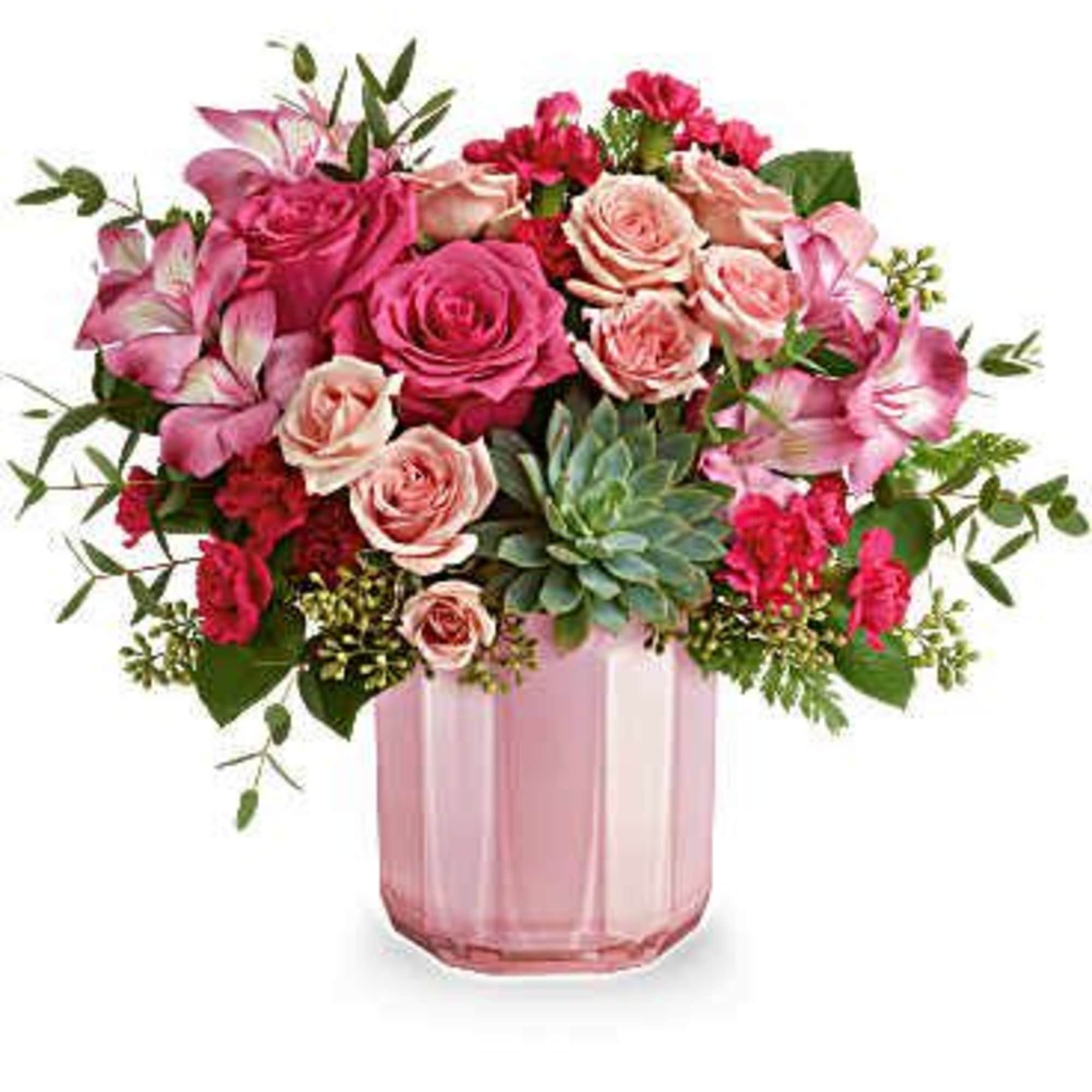 Pink and blush roses arranged in a pink glass vase