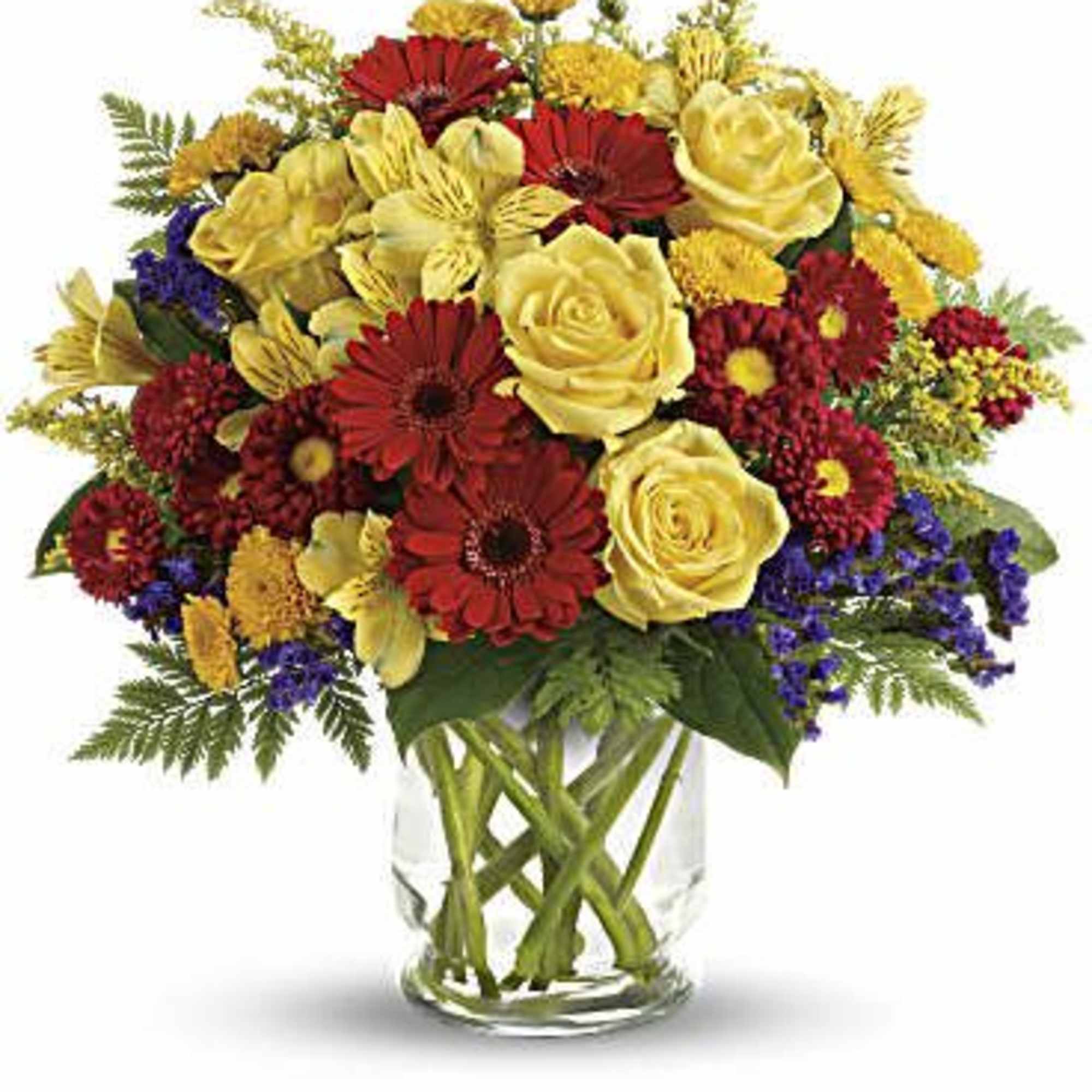 Mixed bouquet of yellow roses, red daisies, and purple filler in a glass vase