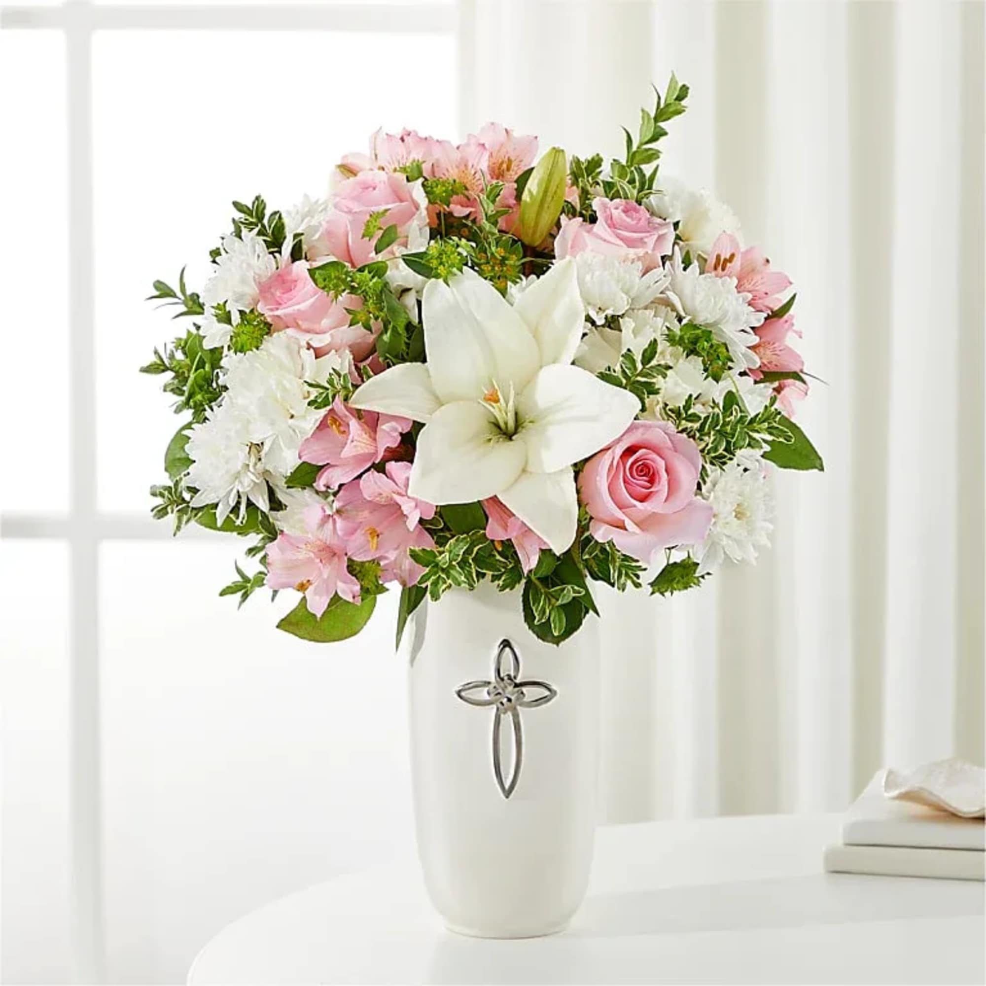Pink and white bouquet in a white vase with a cross emblem