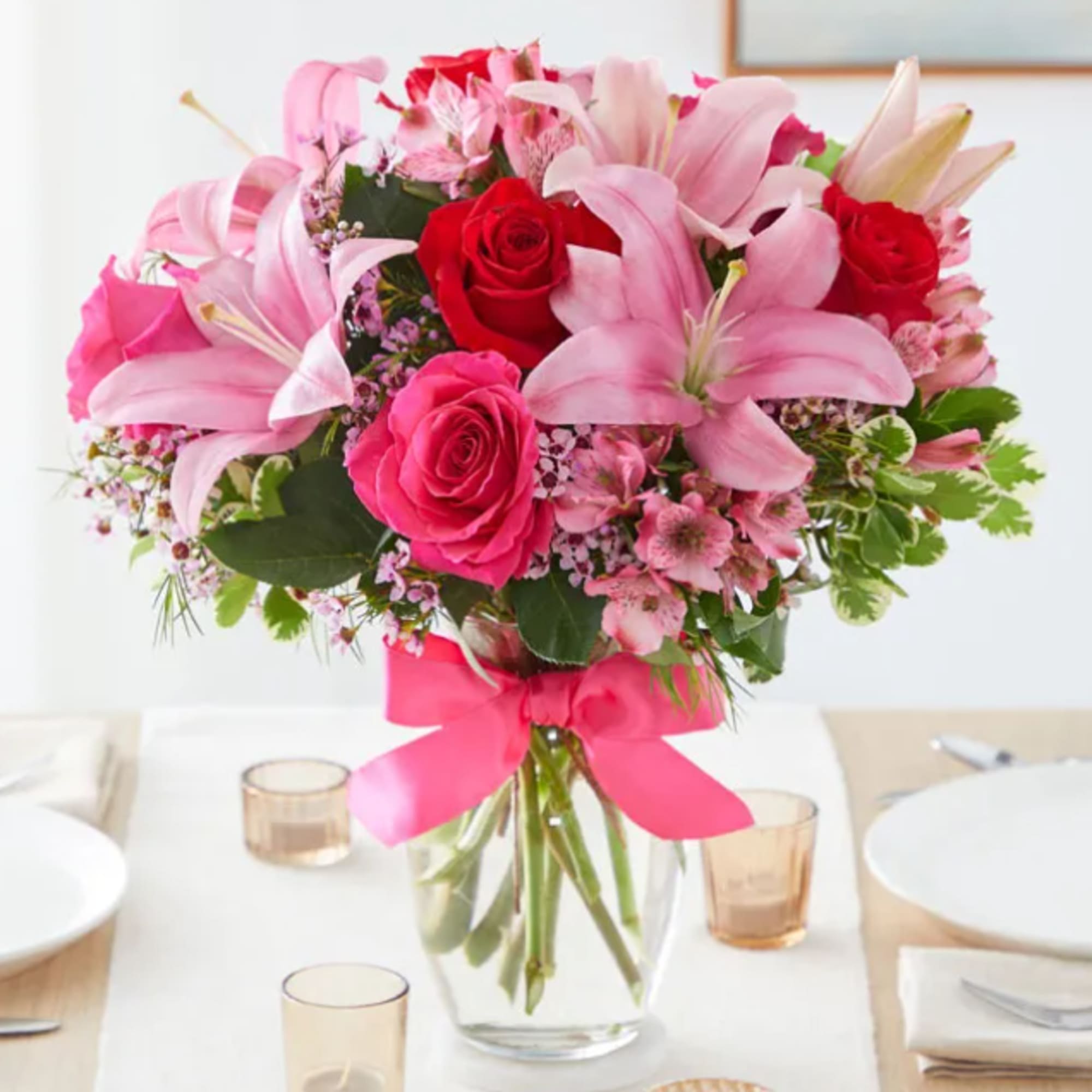 Pink and red flower bouquet in a clear glass vase with a ribbon