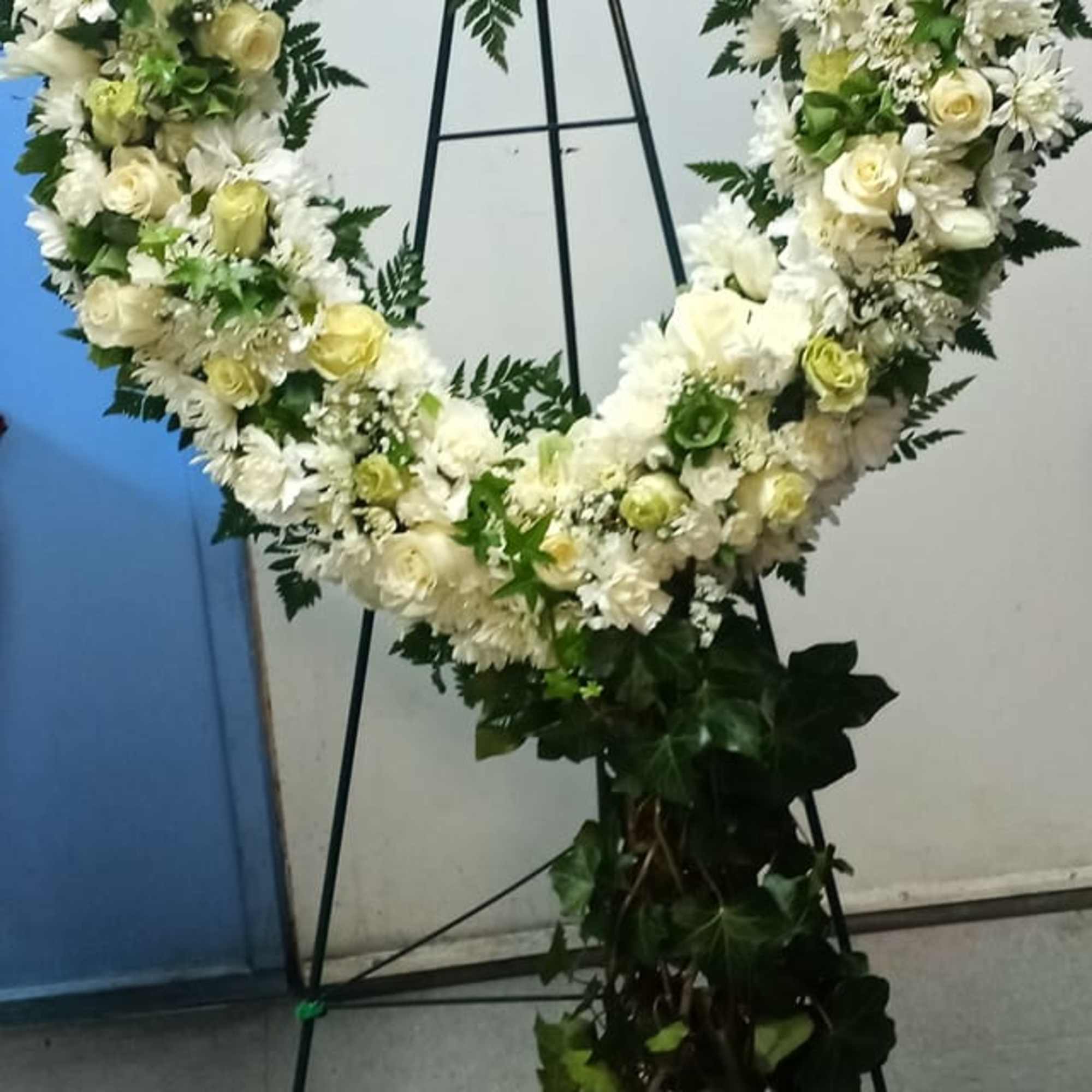 Heart-shaped floral wreath of white and cream flowers on a stand