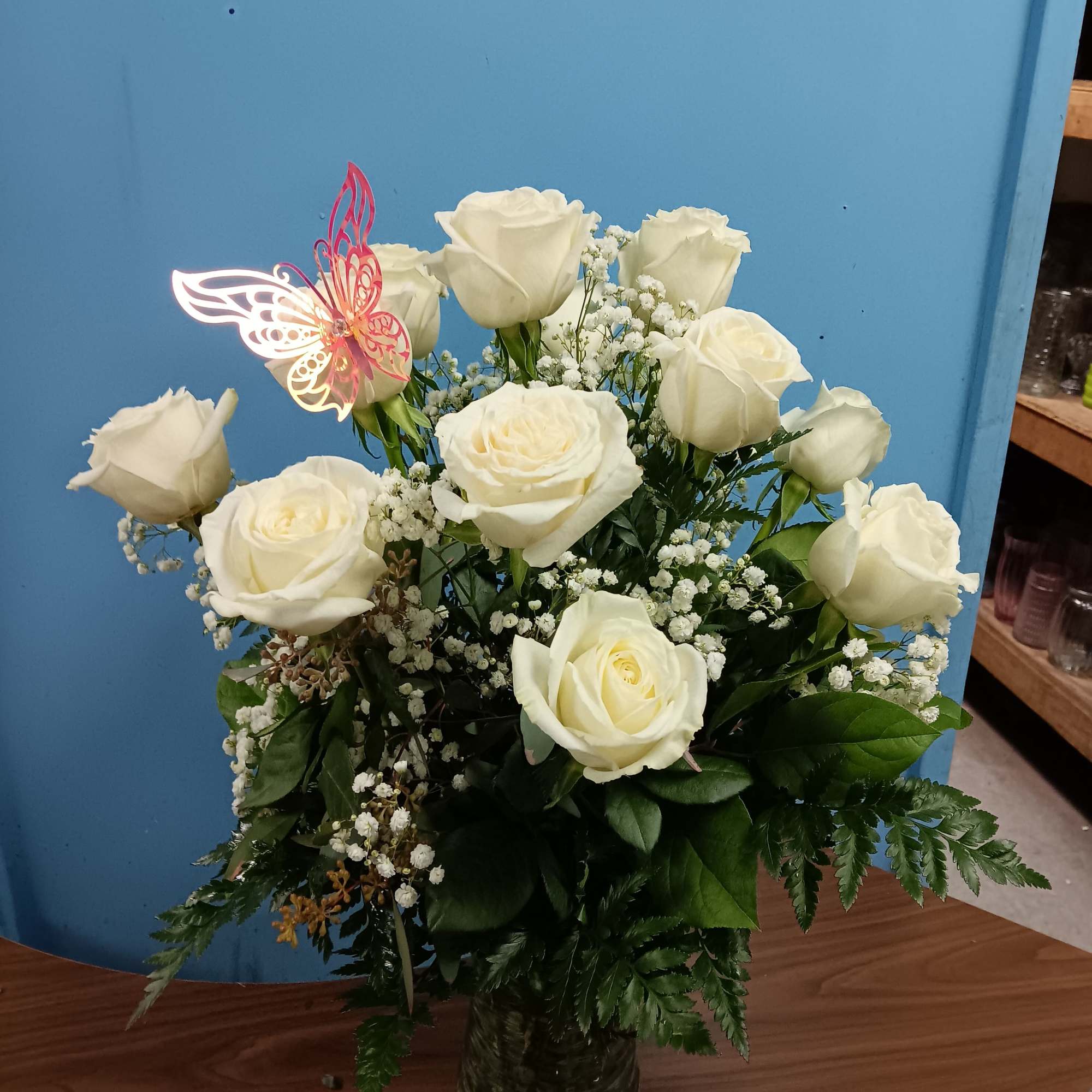 Creamy white roses rise on long stems in a tall textured glass, photo 2 of 2
