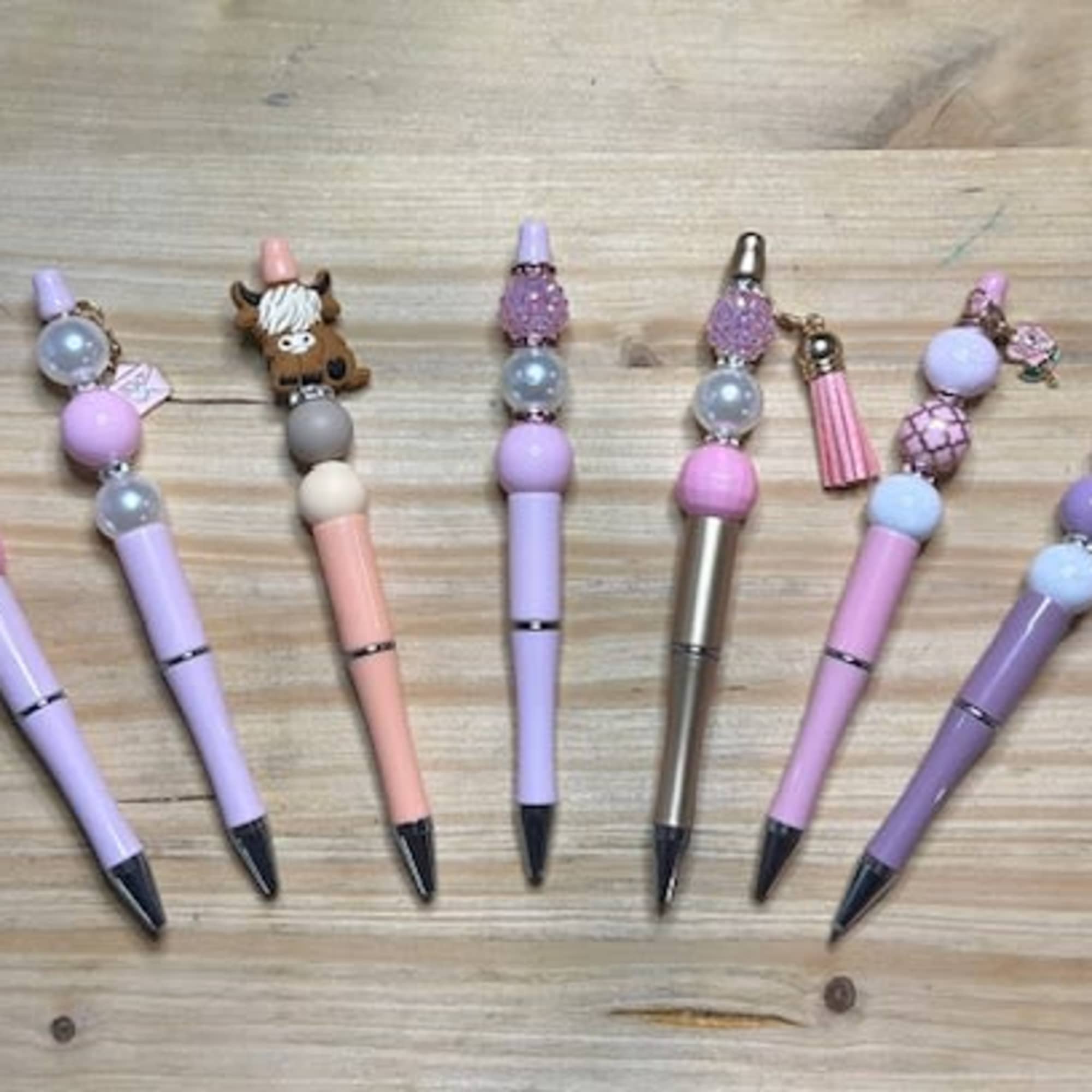 Decorative beaded pens arranged on a wooden surface, photo 3 of 3