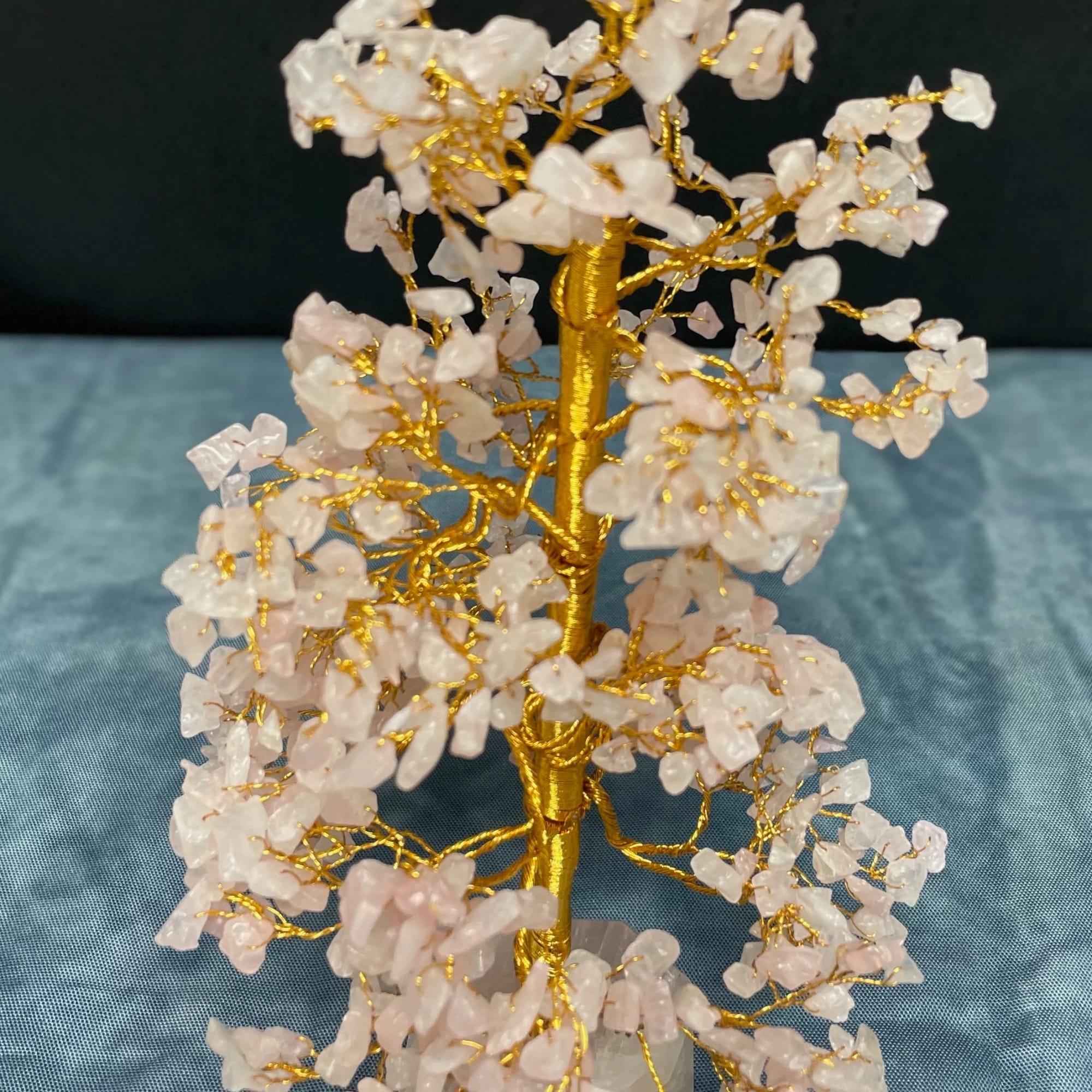 Gold wire tree sculpture with pale pink crystal chips on a stone base