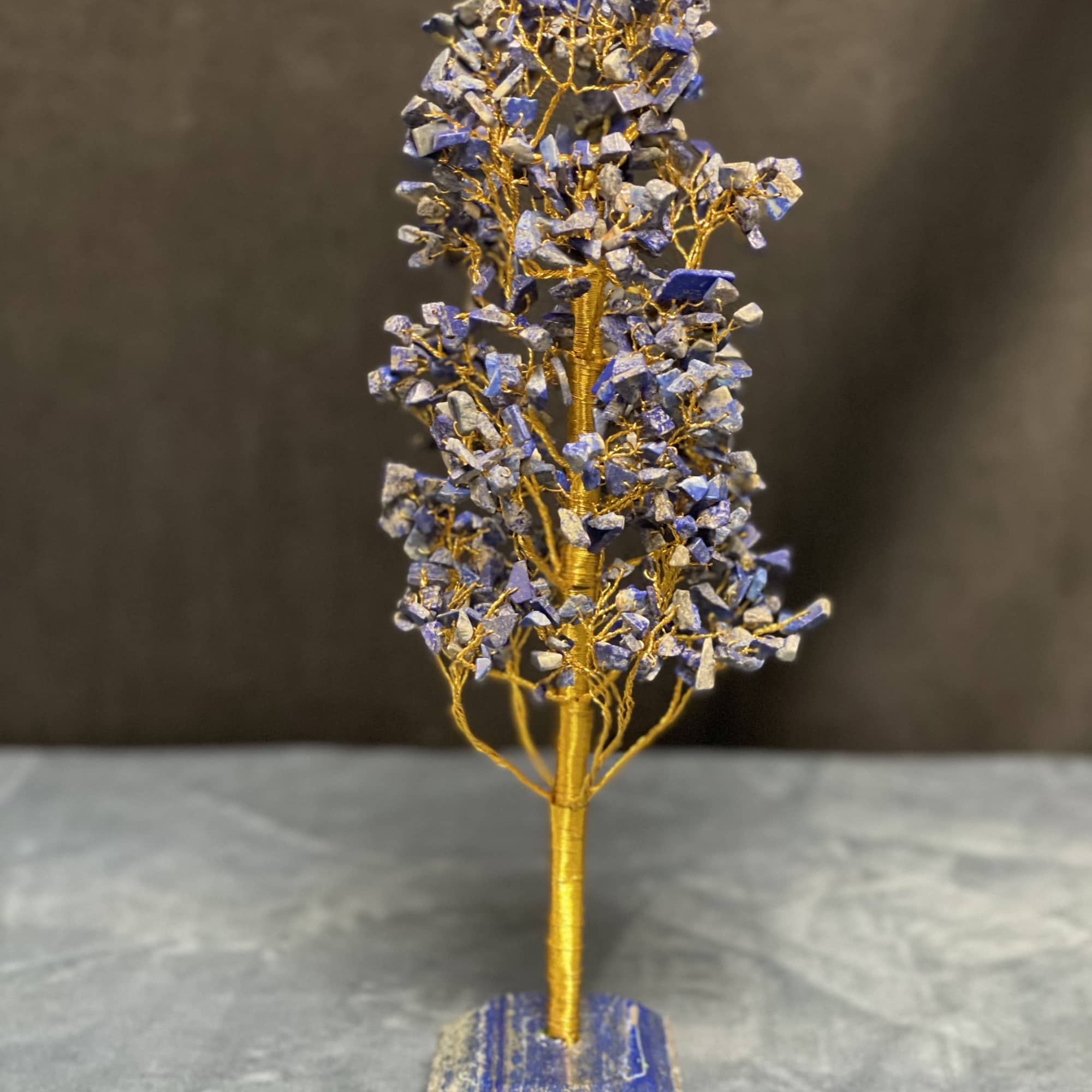 Decorative wire tree with blue stone chips on a matching stone base