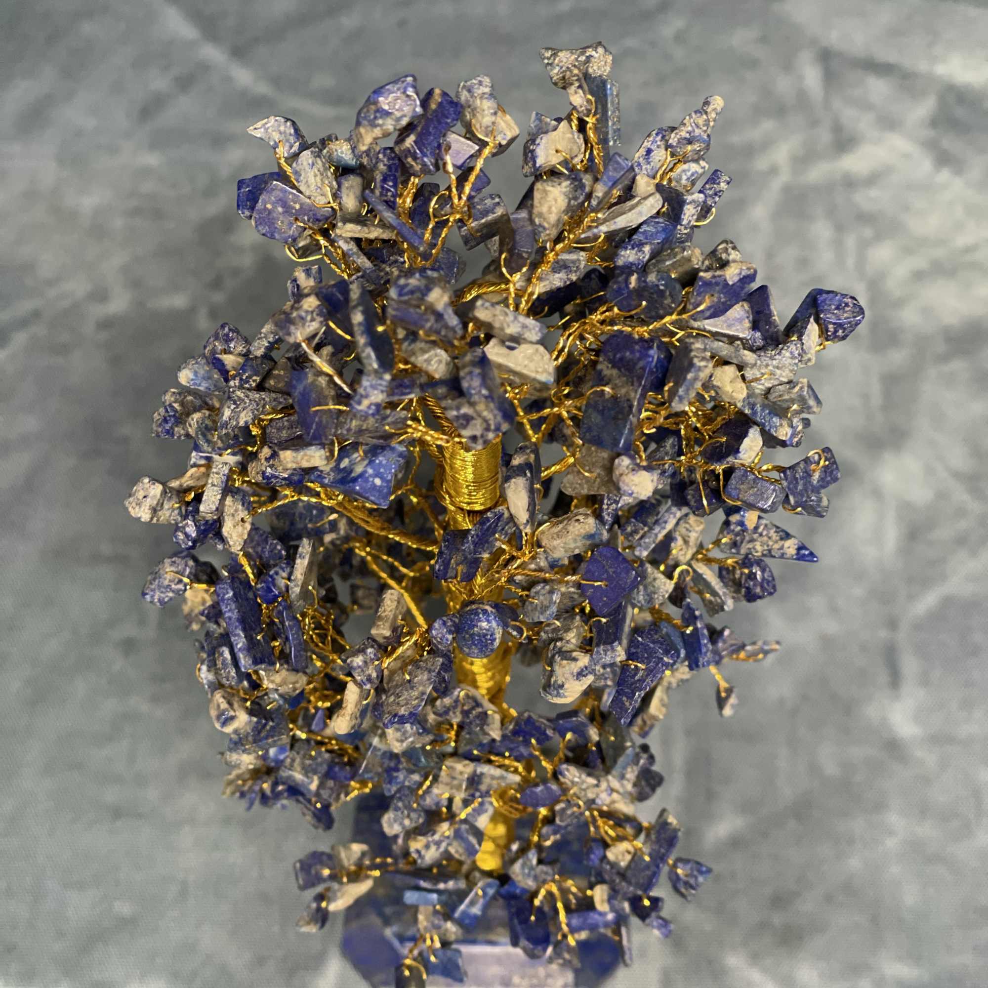 Small wire tree sculpture with blue stone chips on a faceted stone base