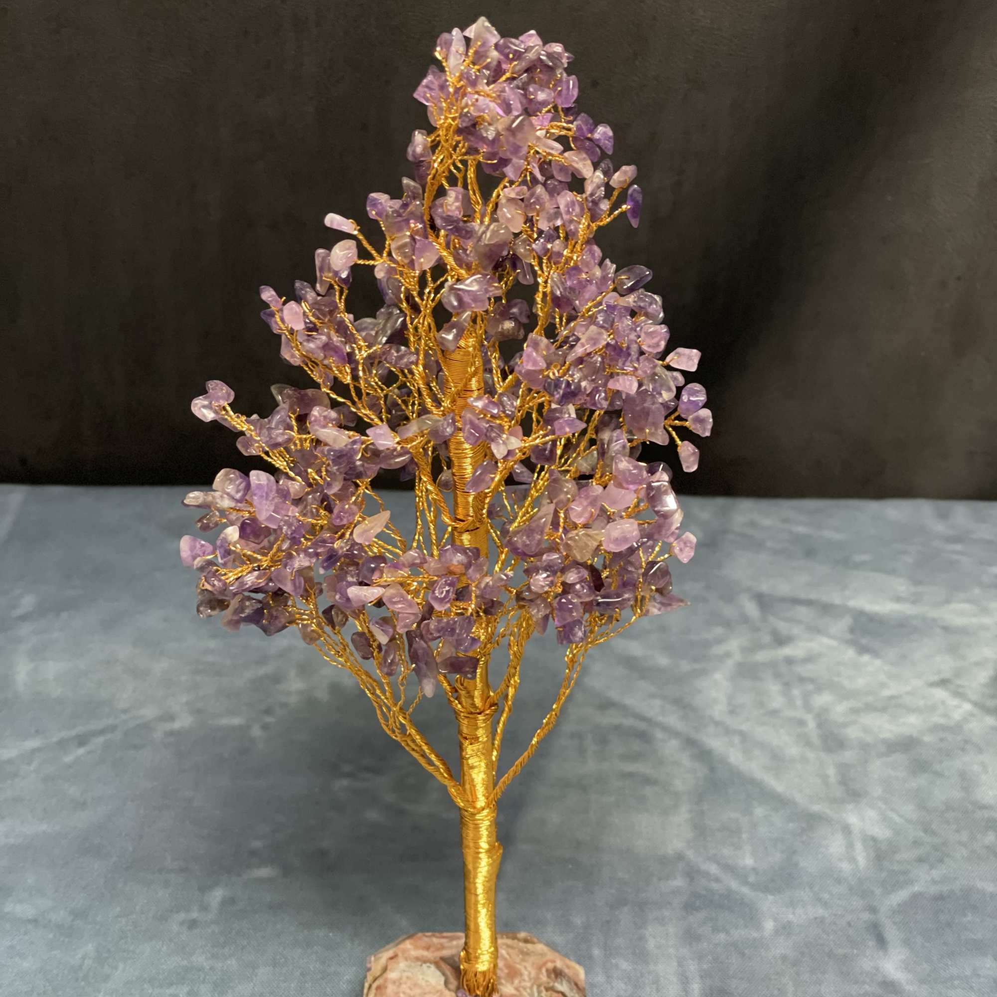 Gold wire gemstone tree sculpture with purple crystal chips on a stone base