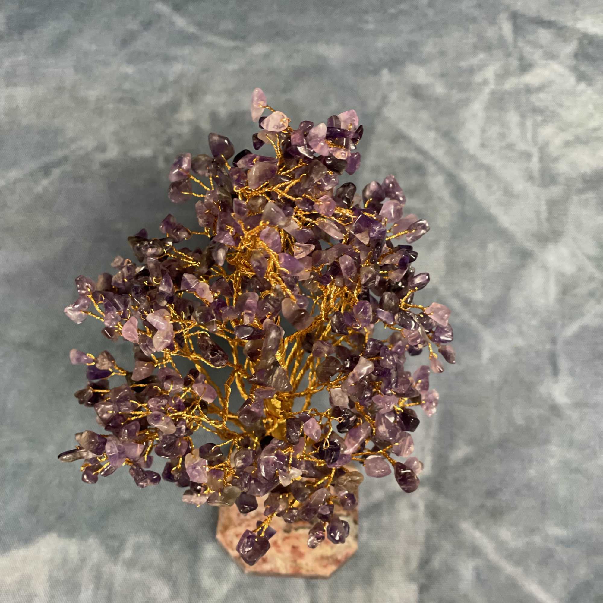 Small decorative tree with purple crystal-like beads on gold wire branches on a stone base