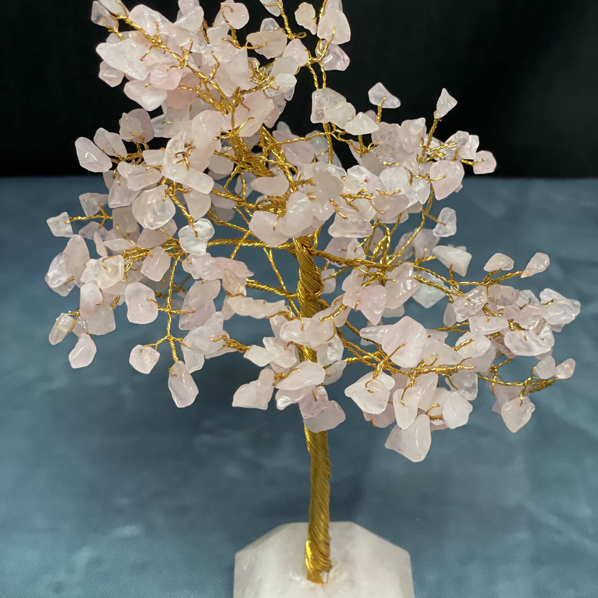 Decorative gemstone tree with pale pink crystal leaves on a white stone base