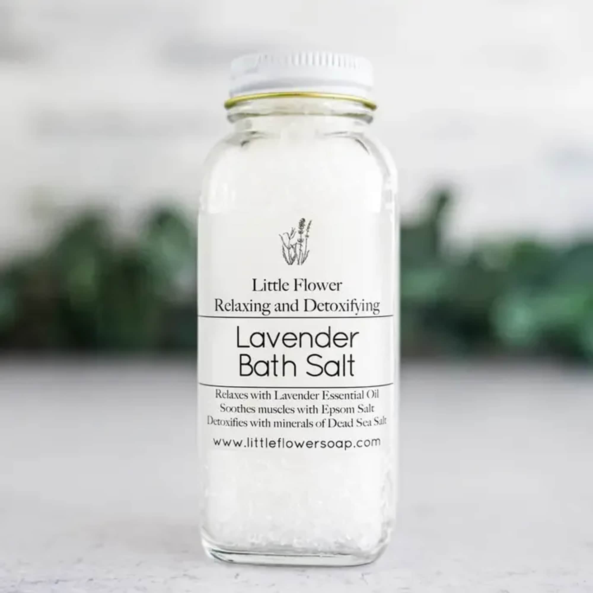 Glass bottle of white lavender bath salts with a black-and-white label on a light surface