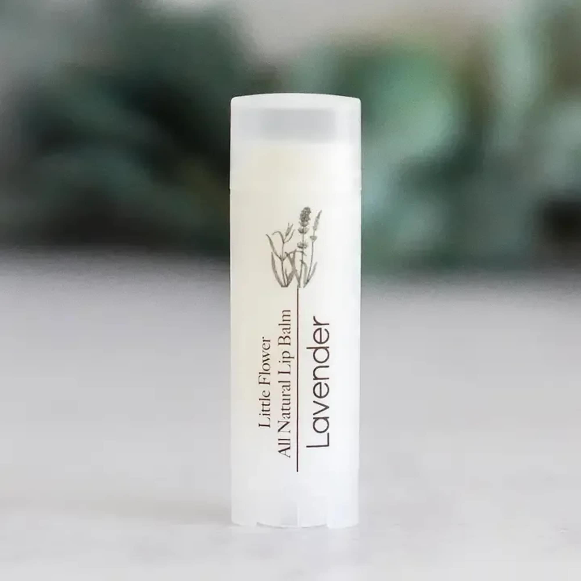 White tube of lavender lip balm standing upright on a light surface.