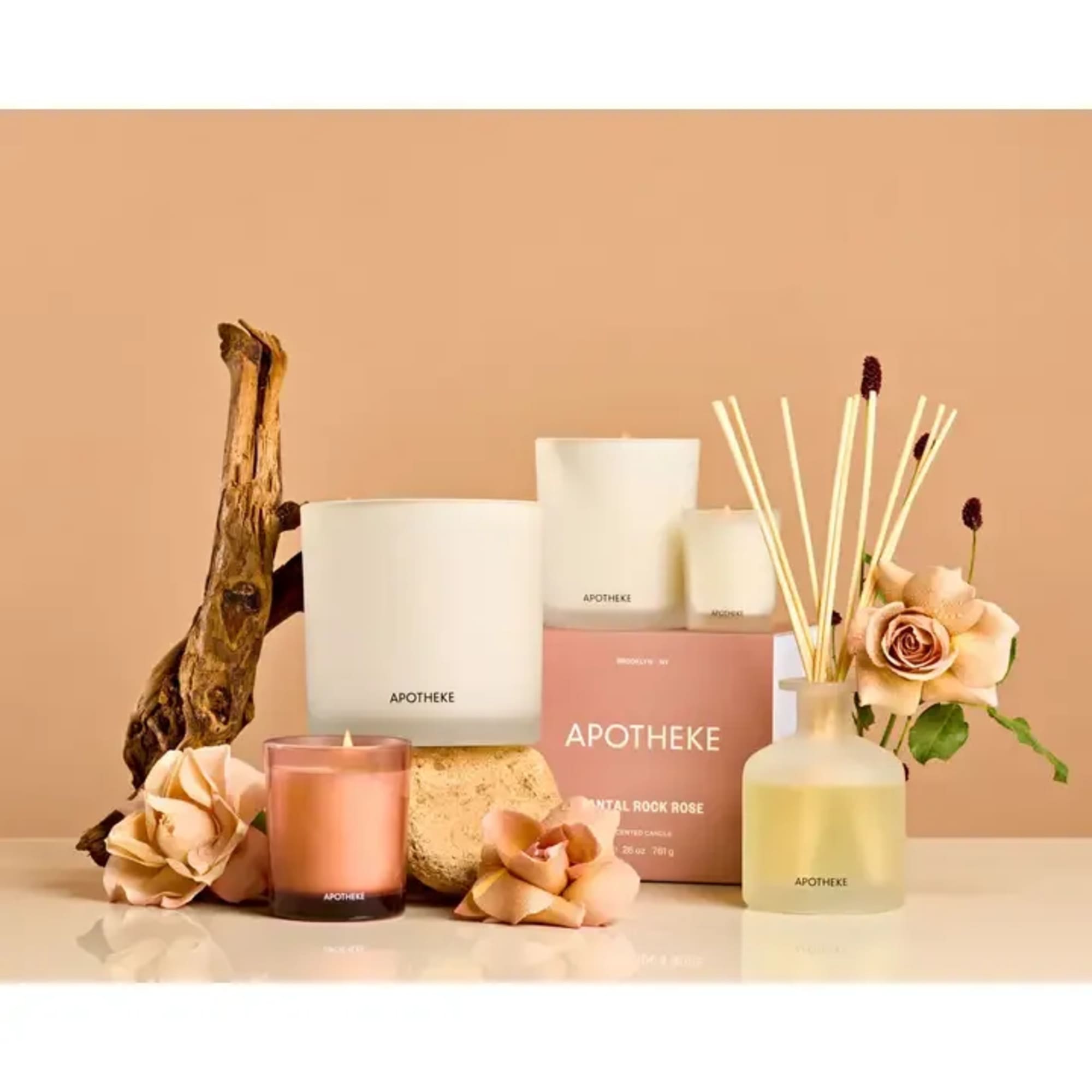 Candle and reed diffuser set with white and rose-gold containers styled with blush roses and driftwood.