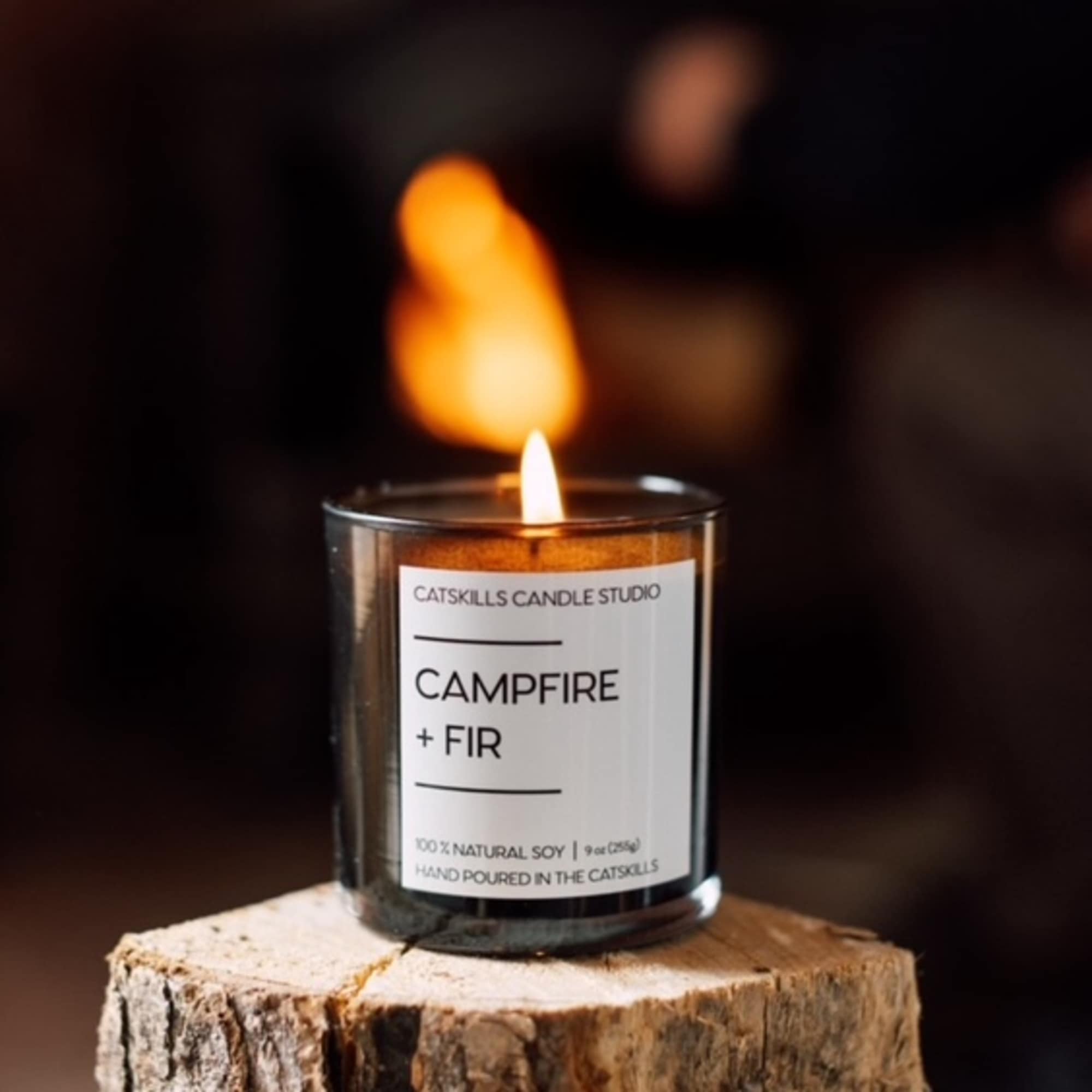 Lit candle in a glass jar on a wood stump