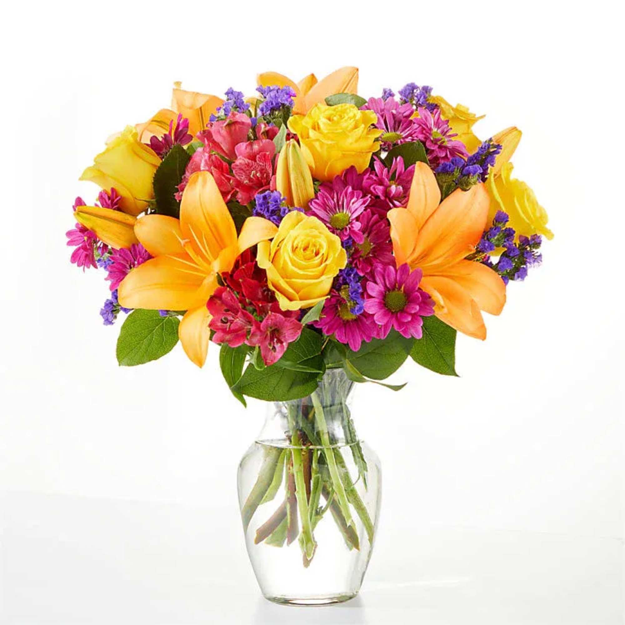 Colorful bouquet of lilies, roses, and daisies in a clear glass vase