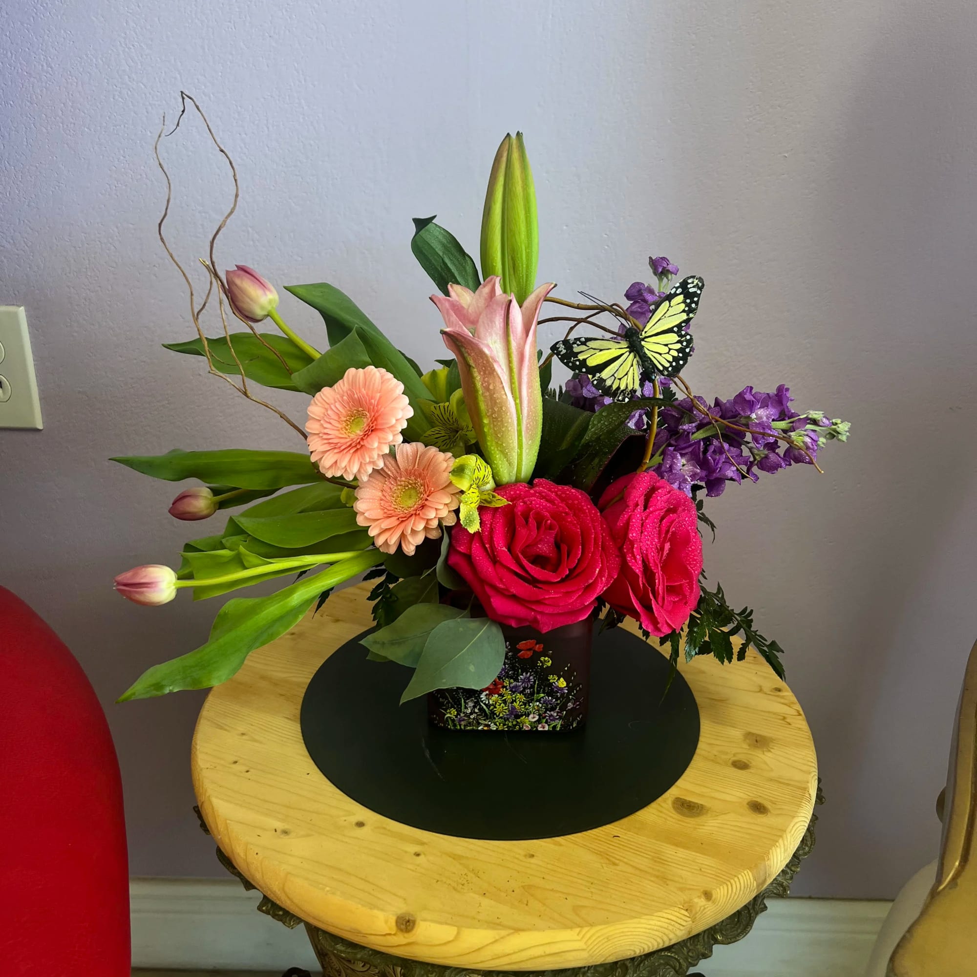 Mixed bouquet with pink roses, lilies, and purple flowers in a square vase