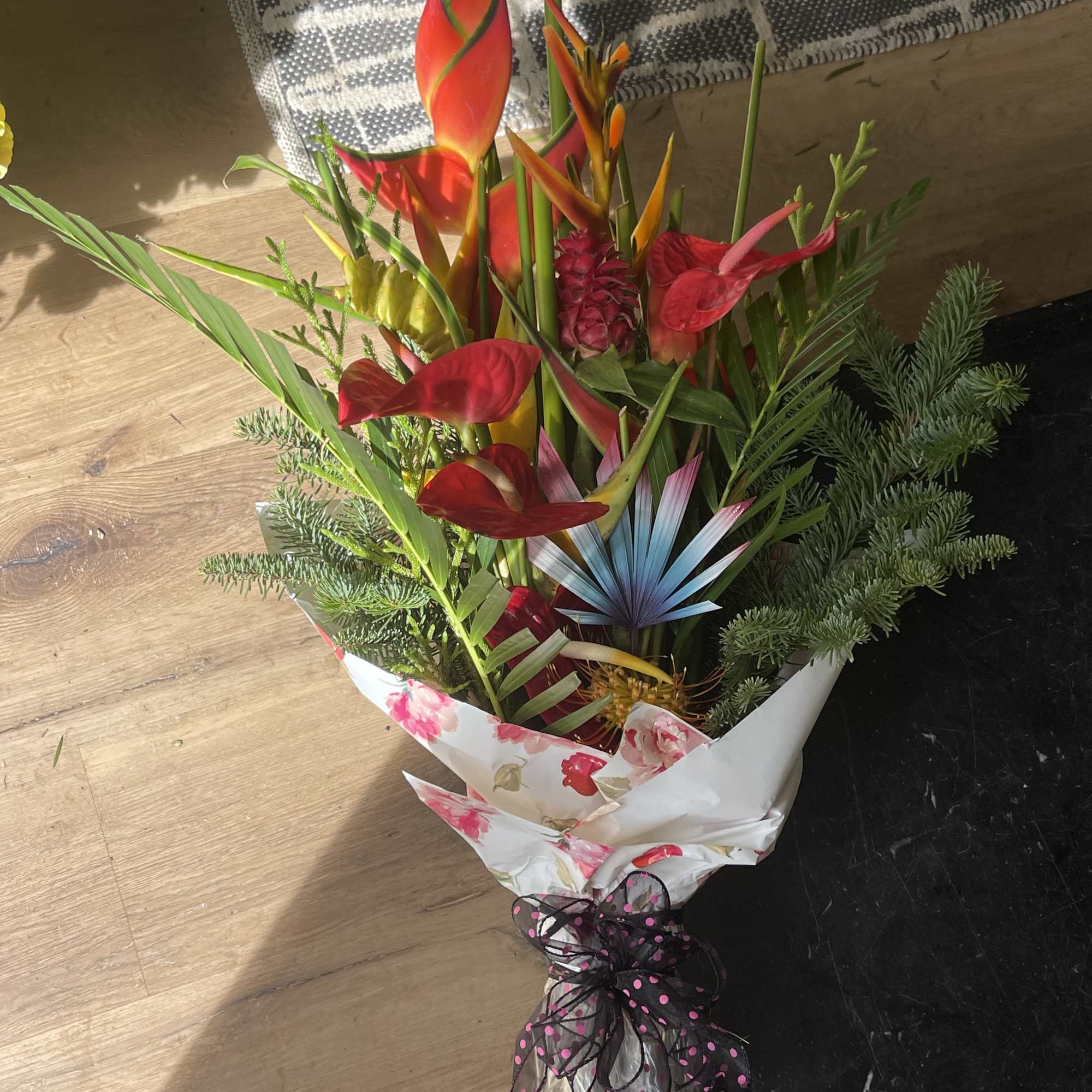 Tropical bouquet with red anthuriums and bird-of-paradise in floral wrap