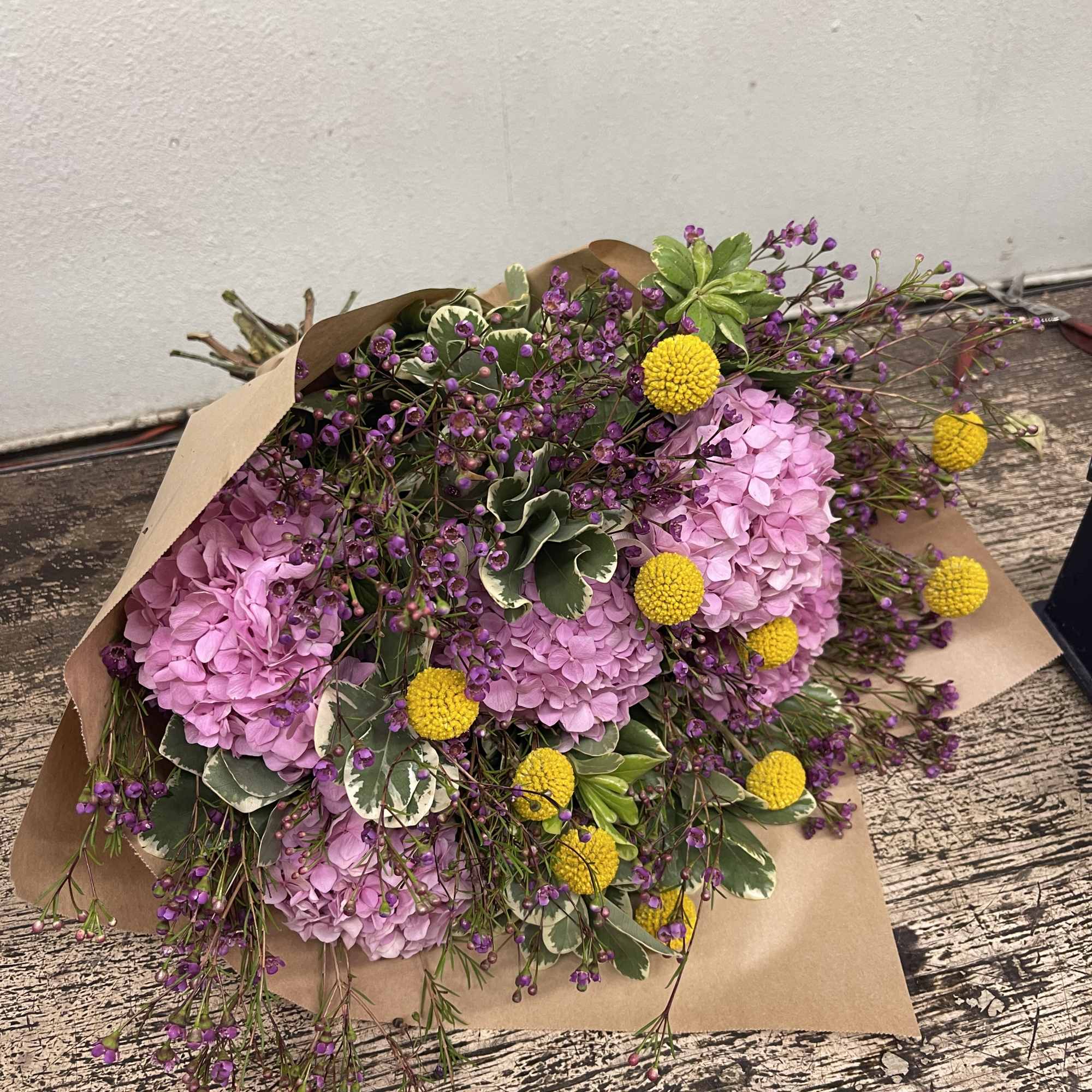 Bouquet of pink hydrangeas with purple filler flowers and yellow billy balls