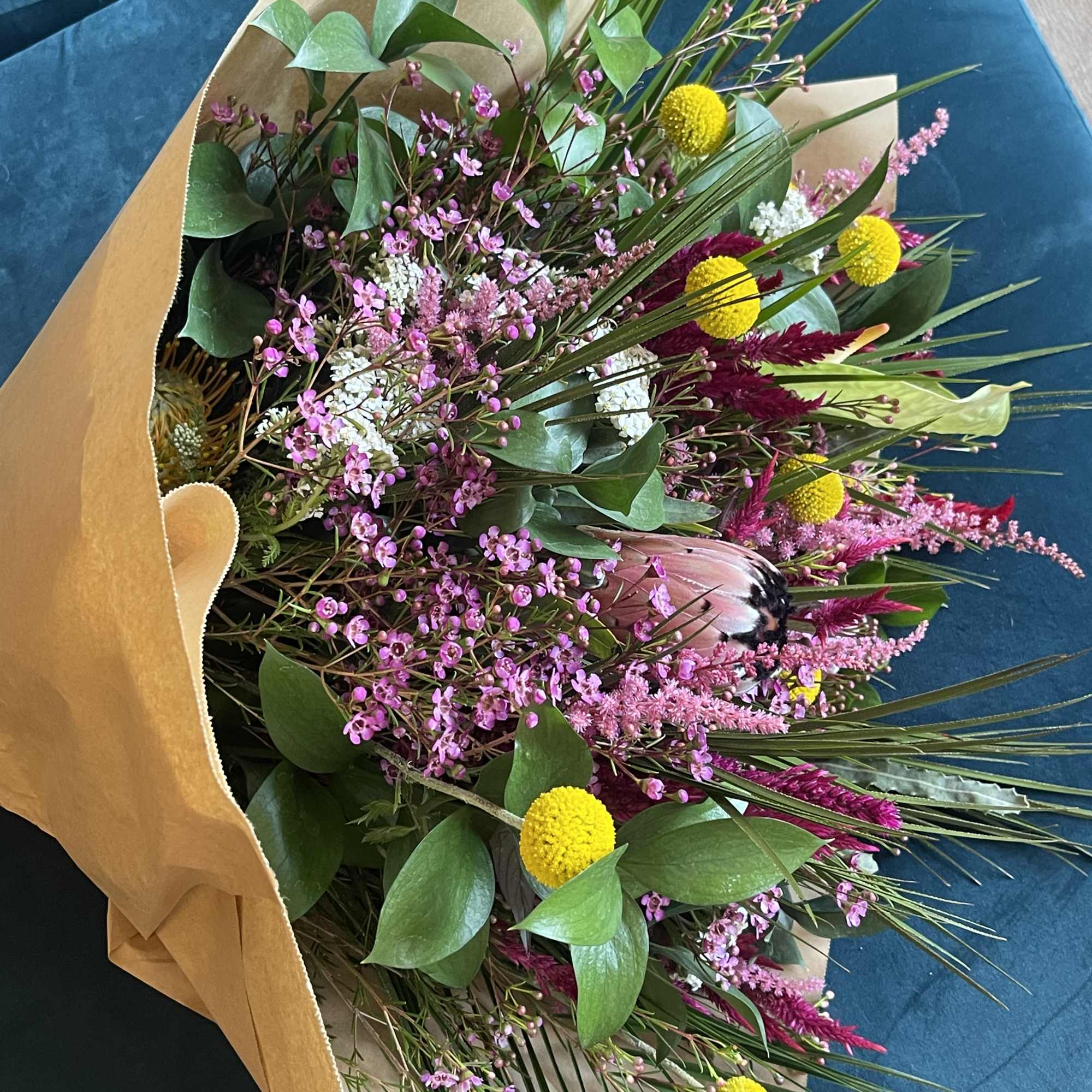 Bouquet of pink and yellow flowers wrapped in kraft paper