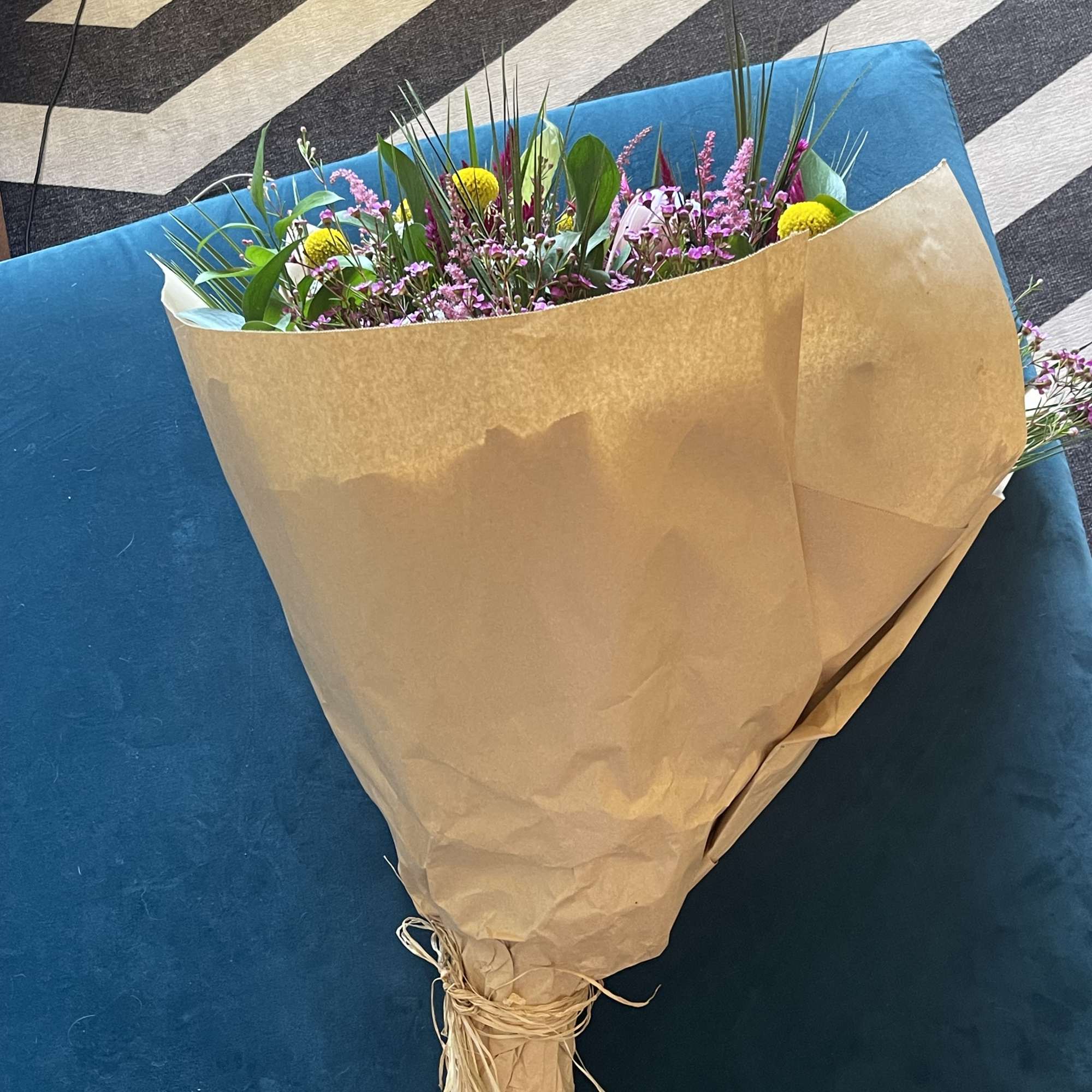 Wrapped bouquet of mixed pink and yellow flowers on a blue chair