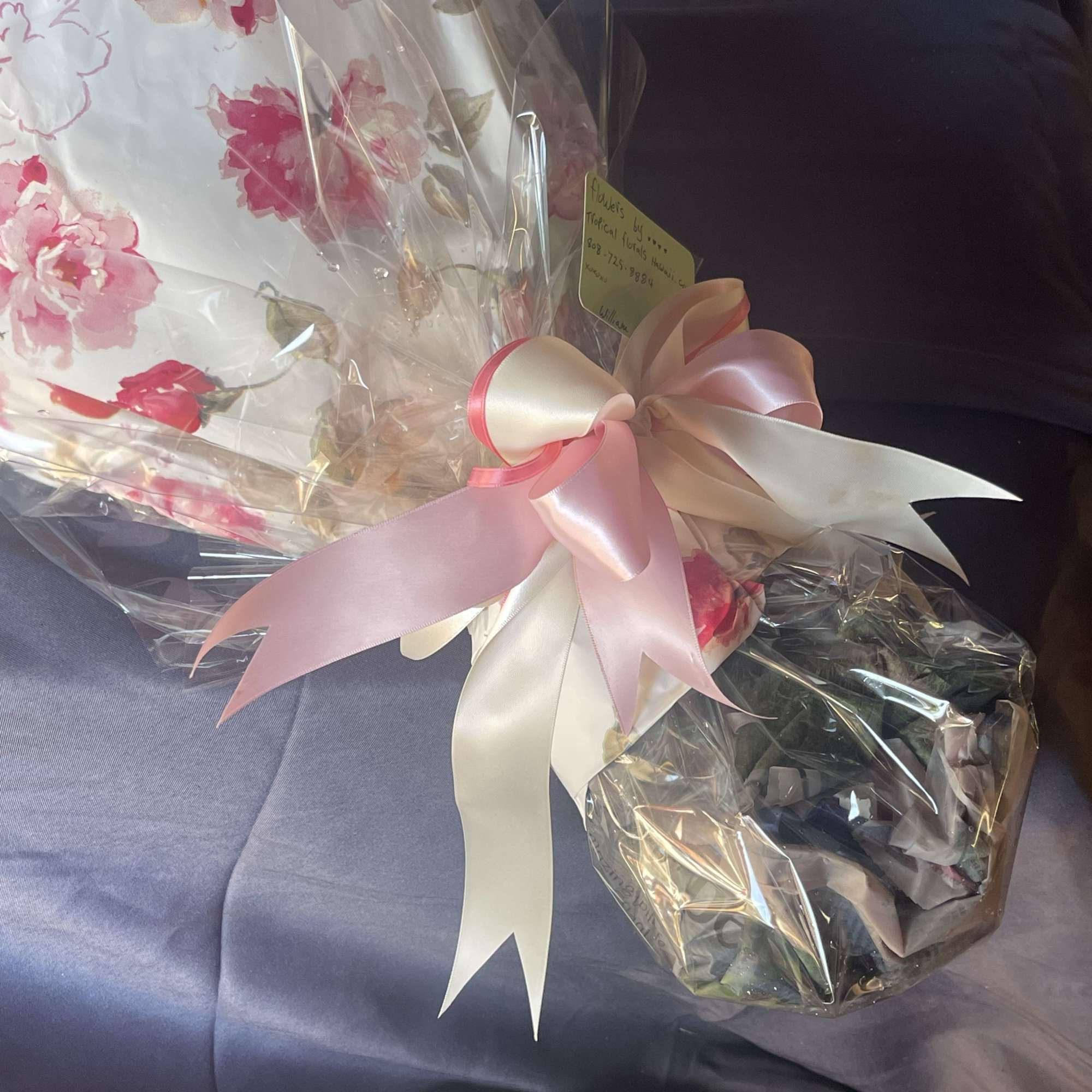 Wrapped bouquet with pink flowers and a large satin ribbon