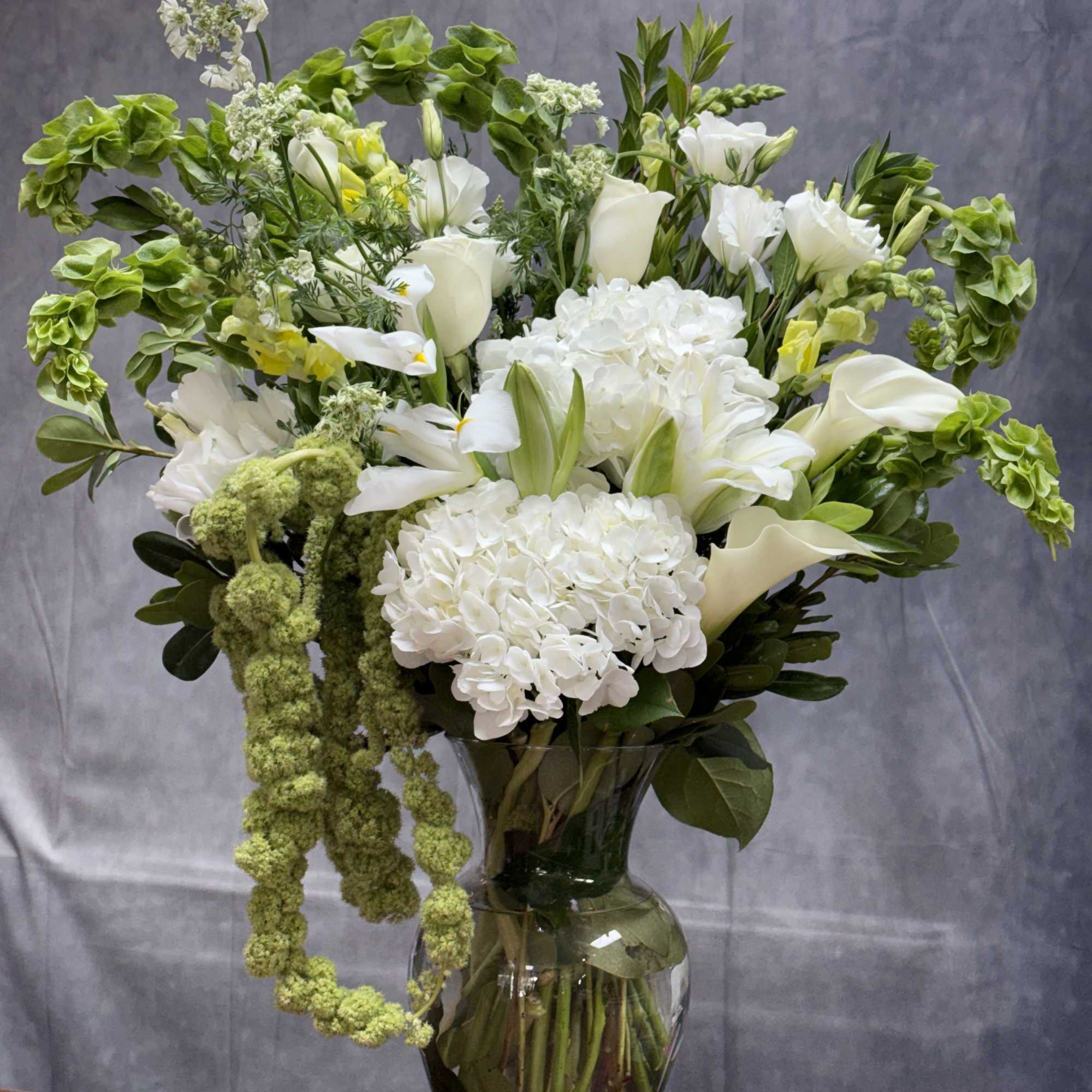 White flowers and green blooms arranged in a glass vase