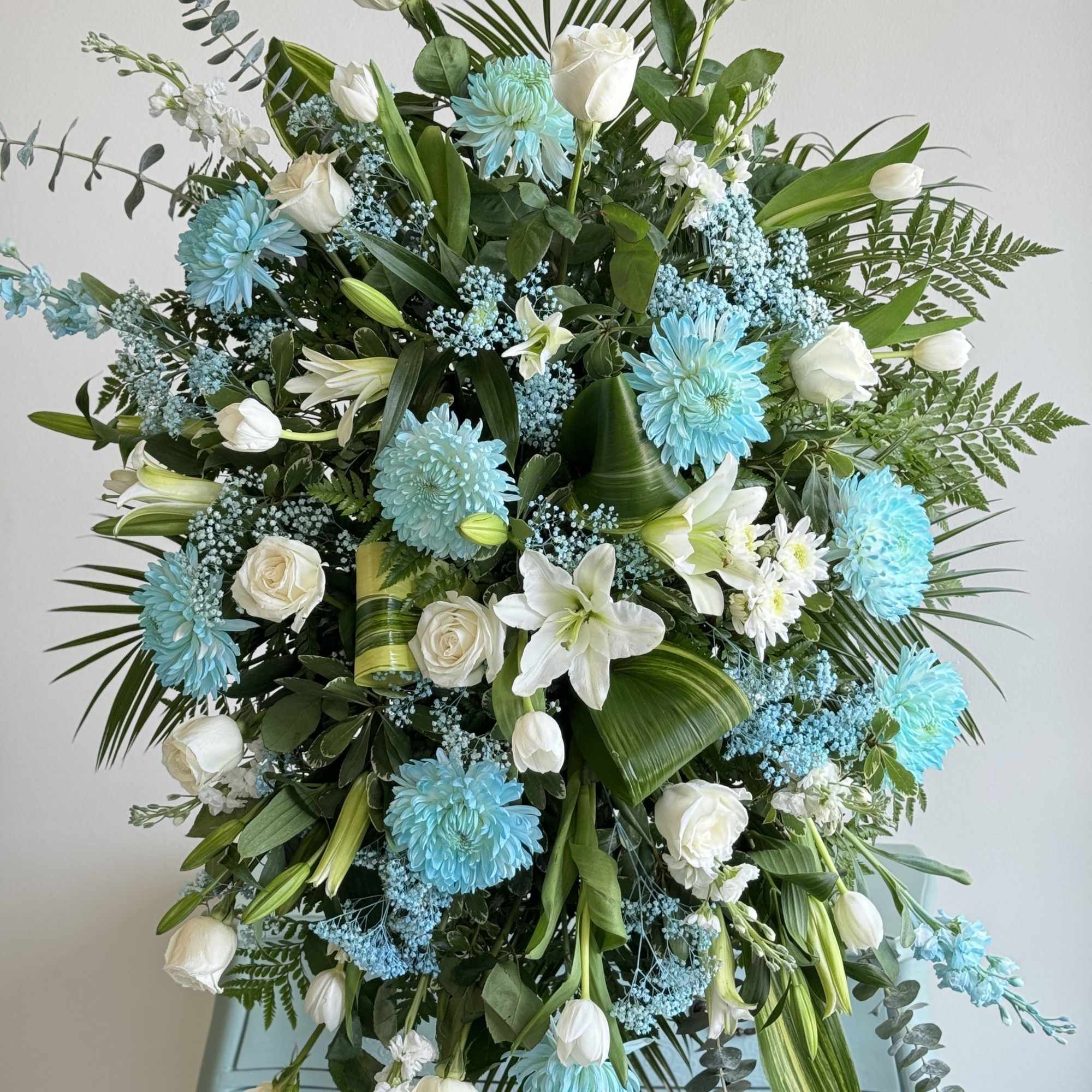 Large floral spray with white roses, lilies, and blue chrysanthemums