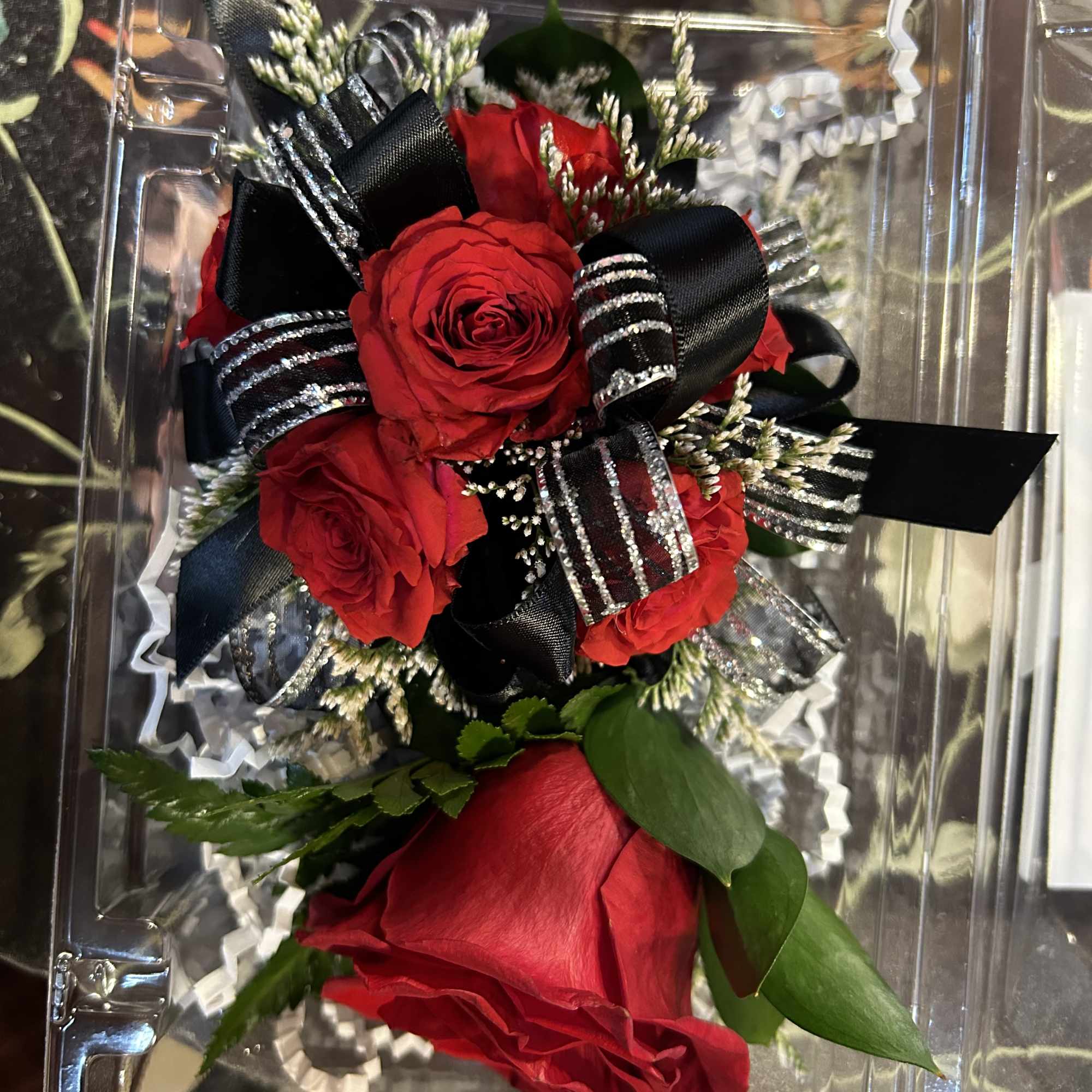 Red roses with black ribbon in a clear plastic box