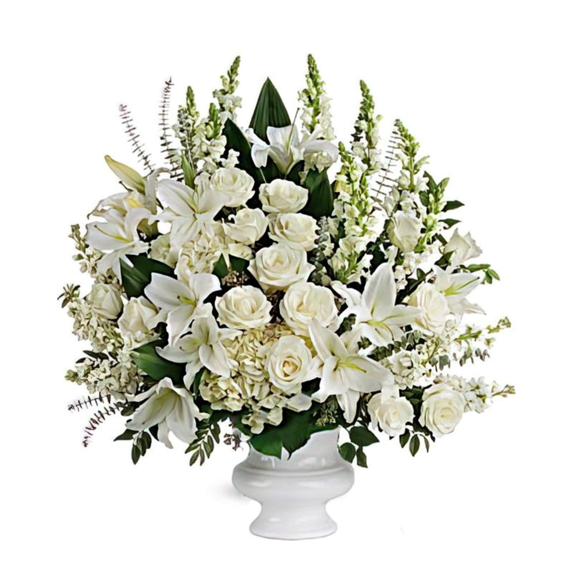 White lilies and roses arranged in a white pedestal vase