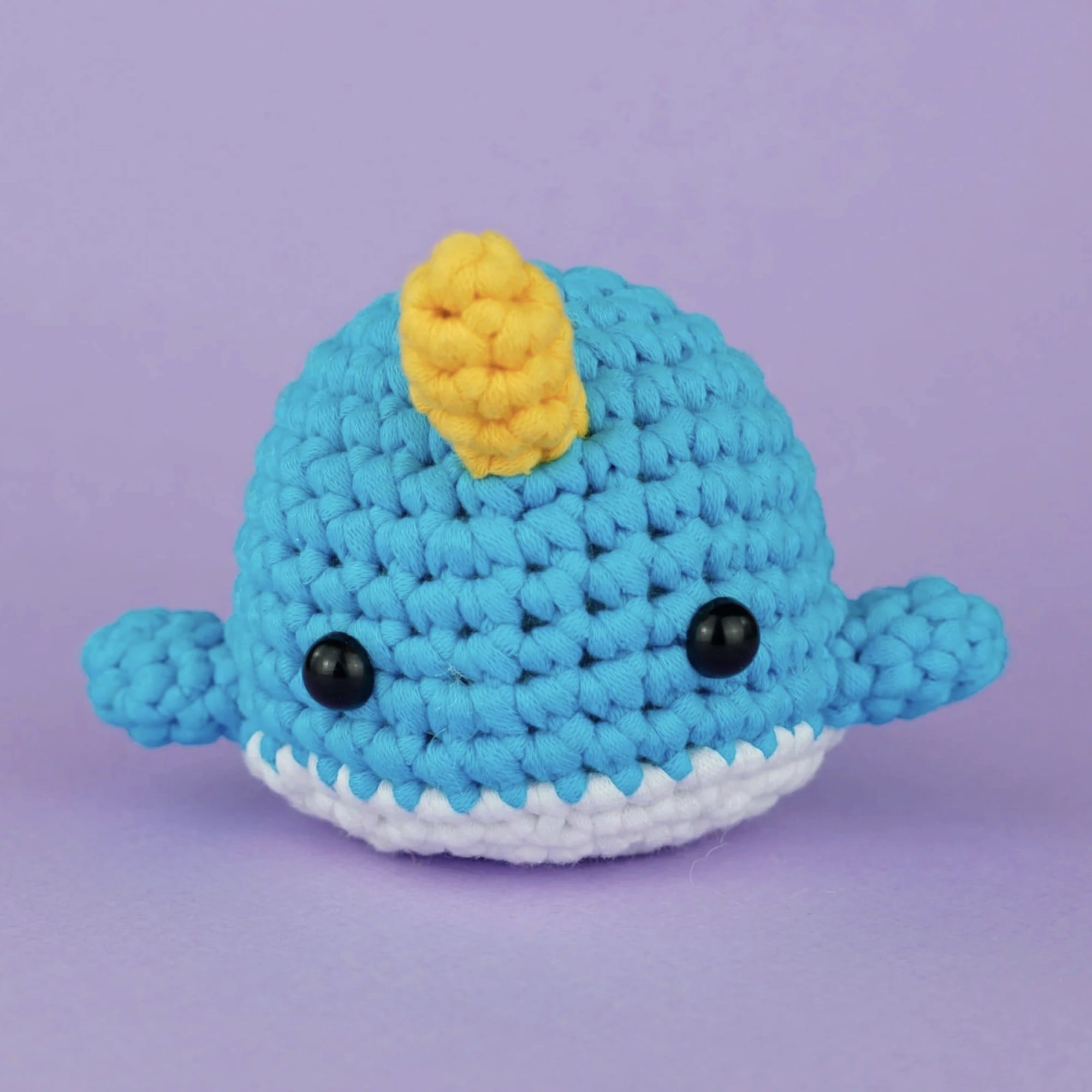 Crocheted blue whale plush with a yellow fin and white belly