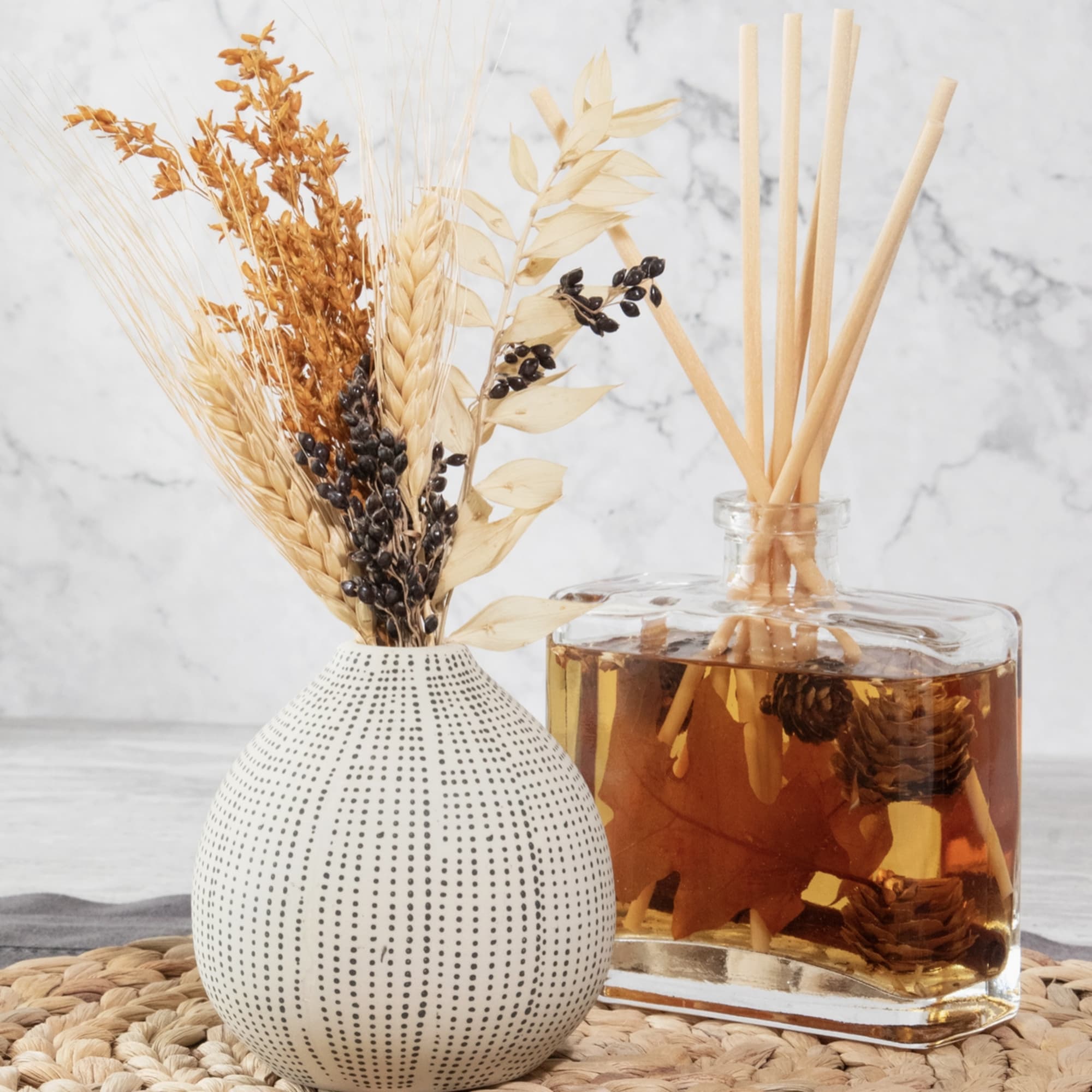Two decorative reed diffusers with dried botanicals in glass containers