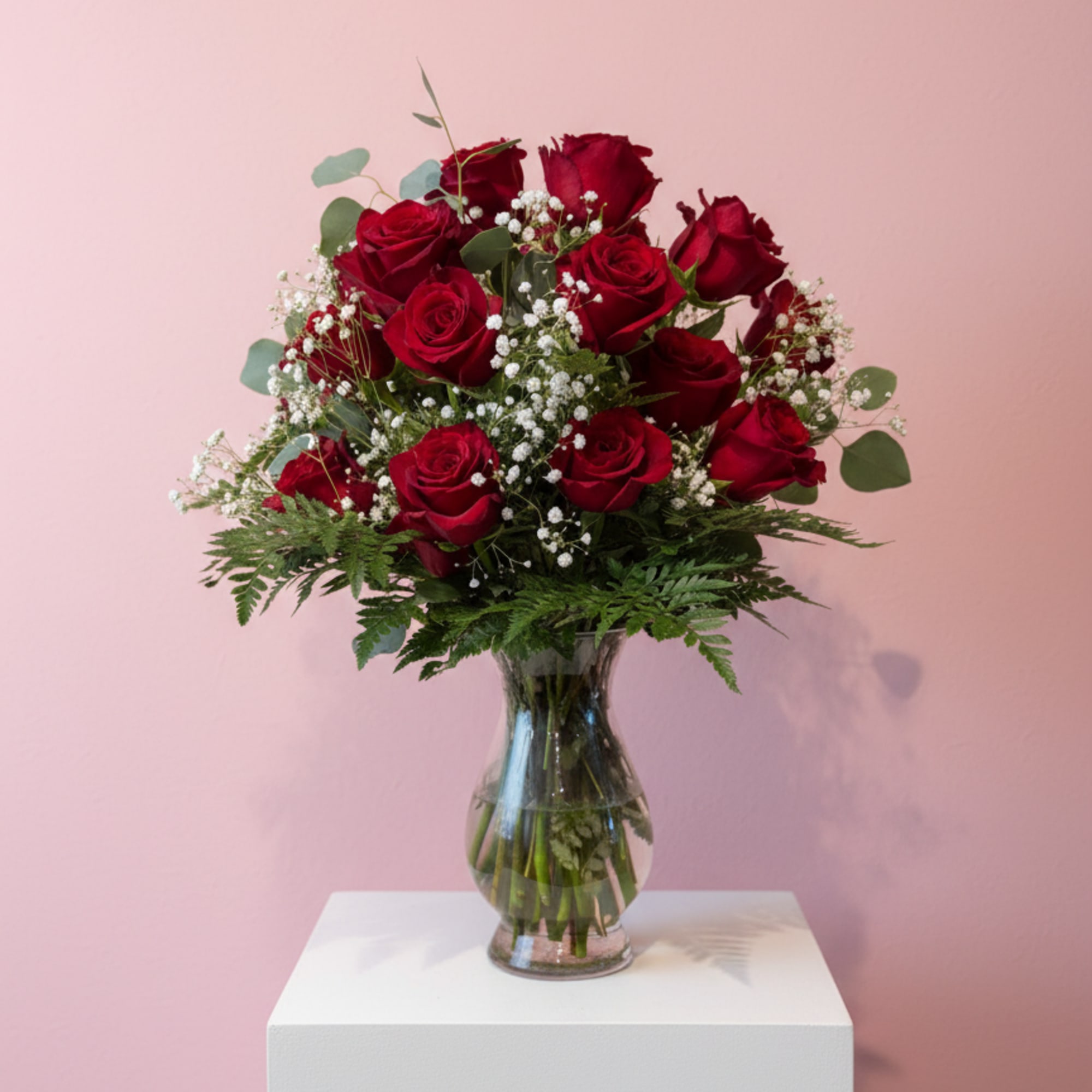 Red roses arranged in a clear glass vase with baby's breath