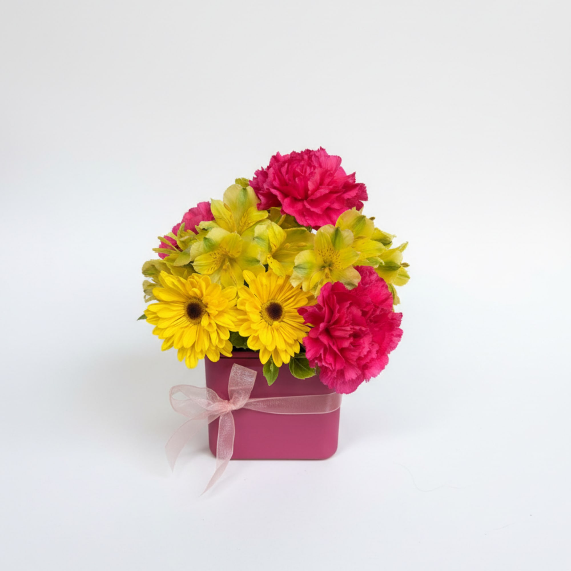 Pink and yellow mixed flowers in a square magenta box with a ribbon