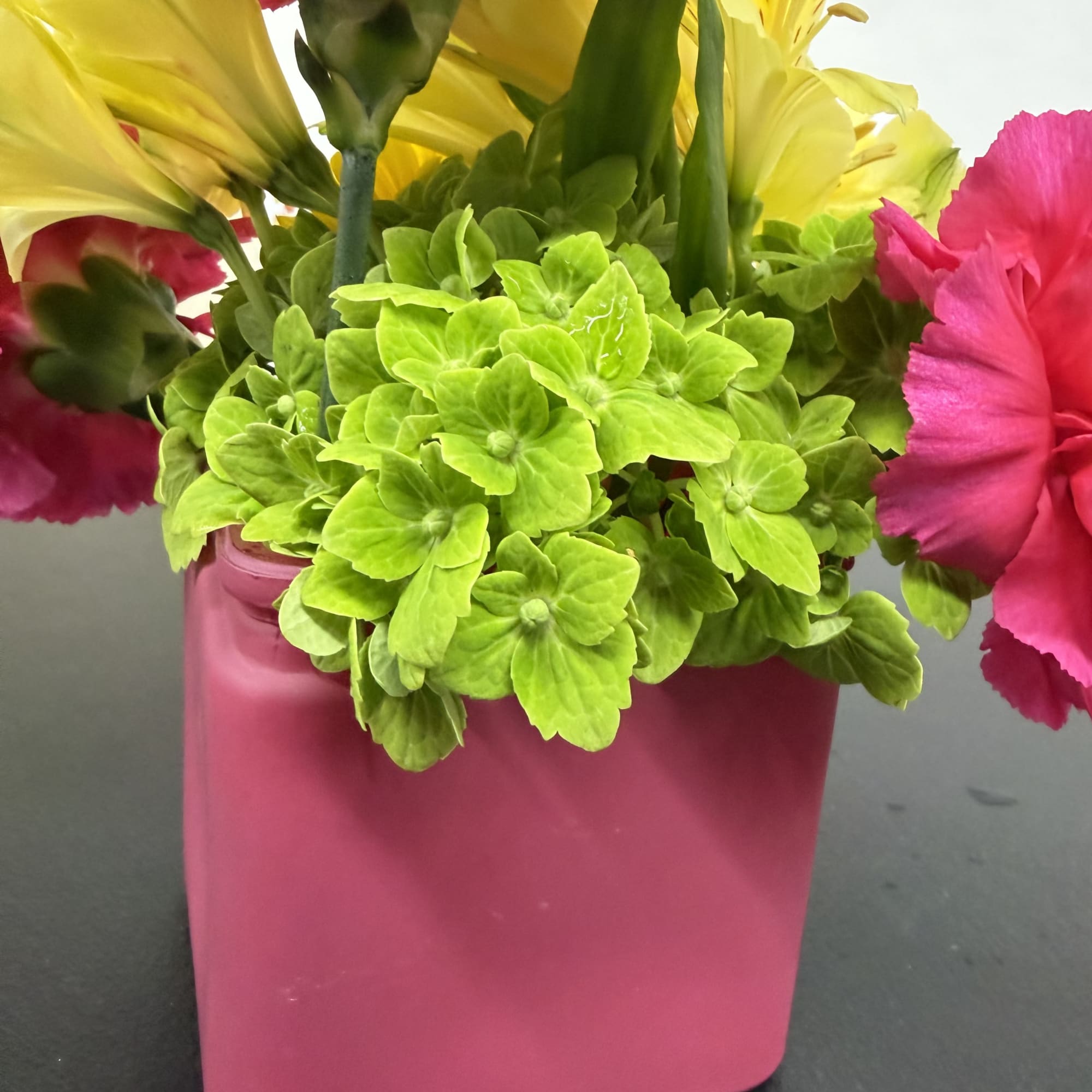 Pink and yellow flowers in a pink rectangular vase