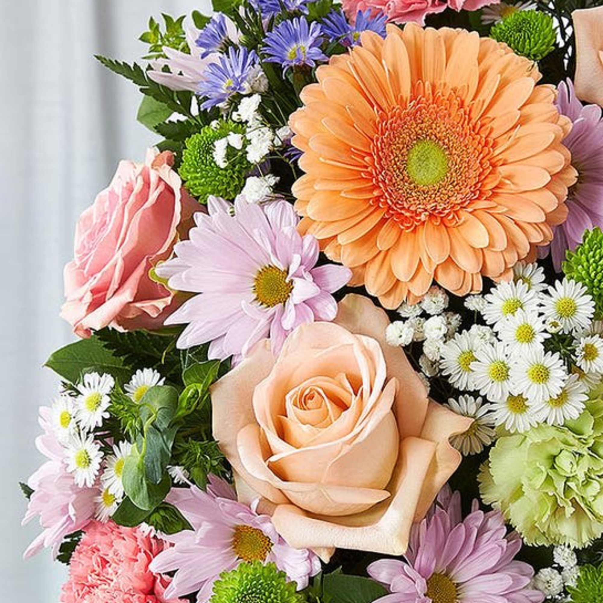 Mixed bouquet with peach roses, gerbera daisies, and pastel daisies