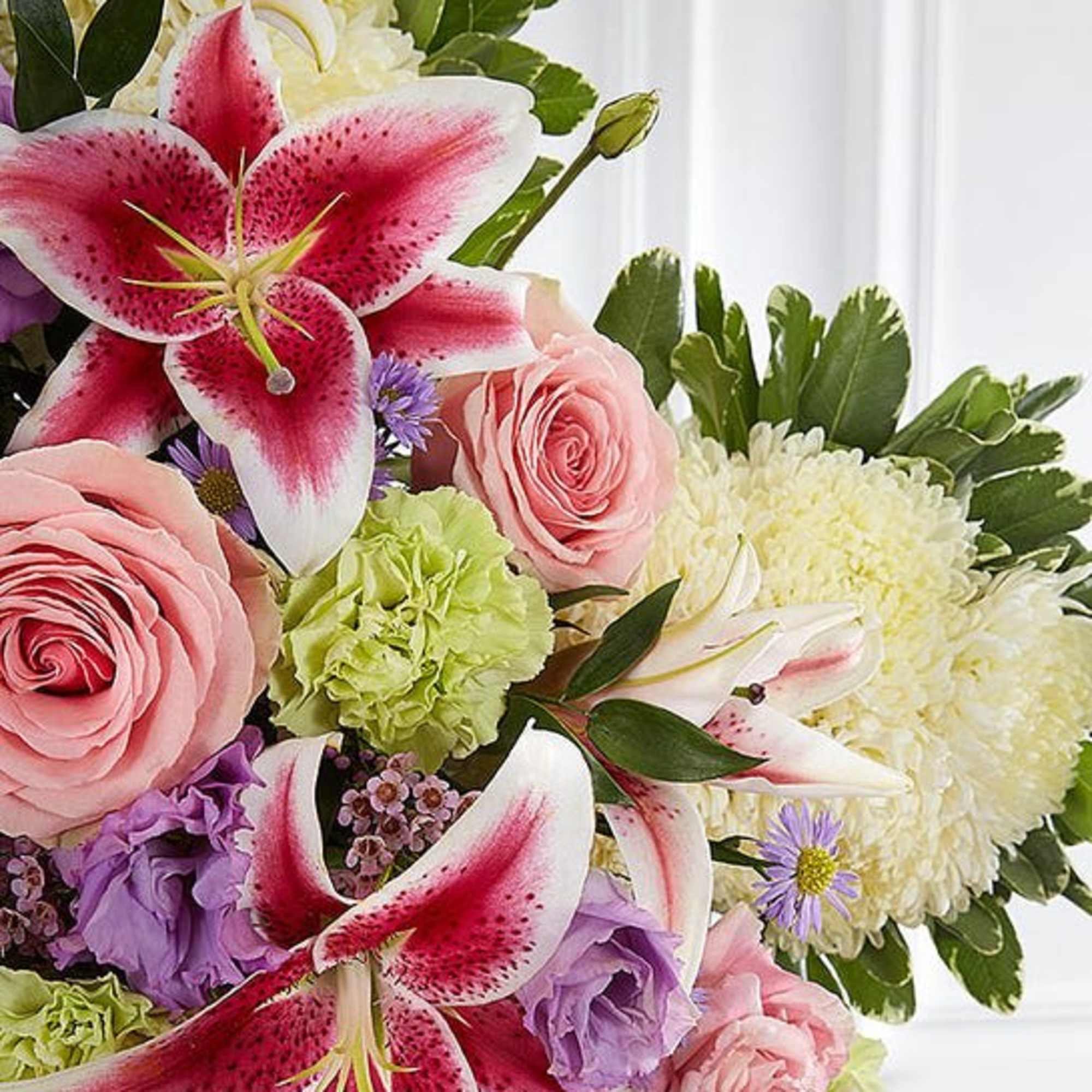Bouquet of pink lilies, roses, and purple blooms with white flowers