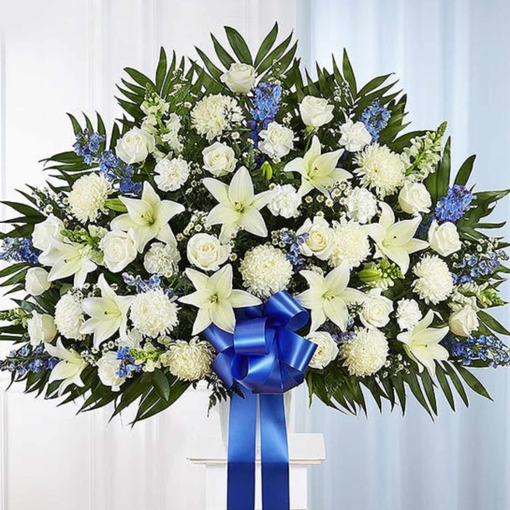 Large white floral standing spray with a blue ribbon bow