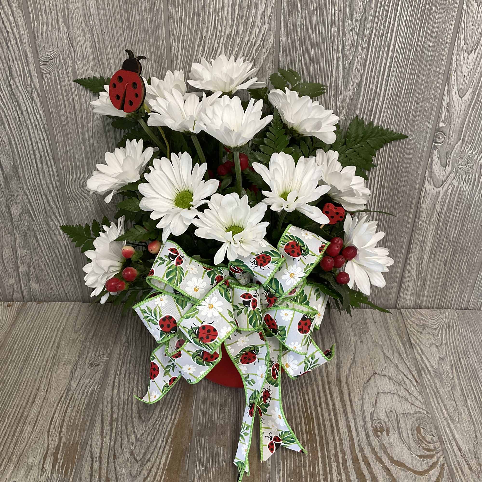White daisy bouquet with a ladybug ribbon and red berry accents