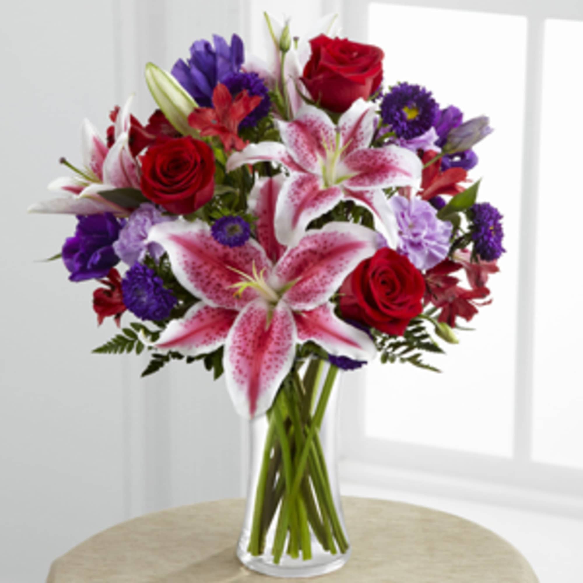Bouquet of red roses and pink lilies in a clear glass vase