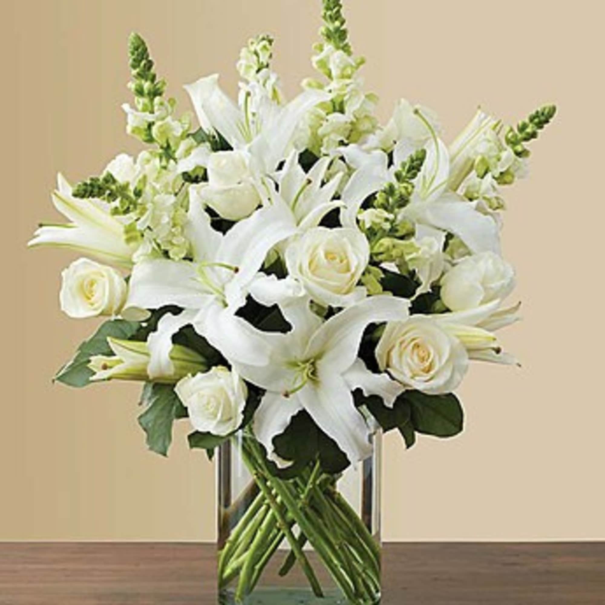 White lilies and roses arranged in a clear glass vase