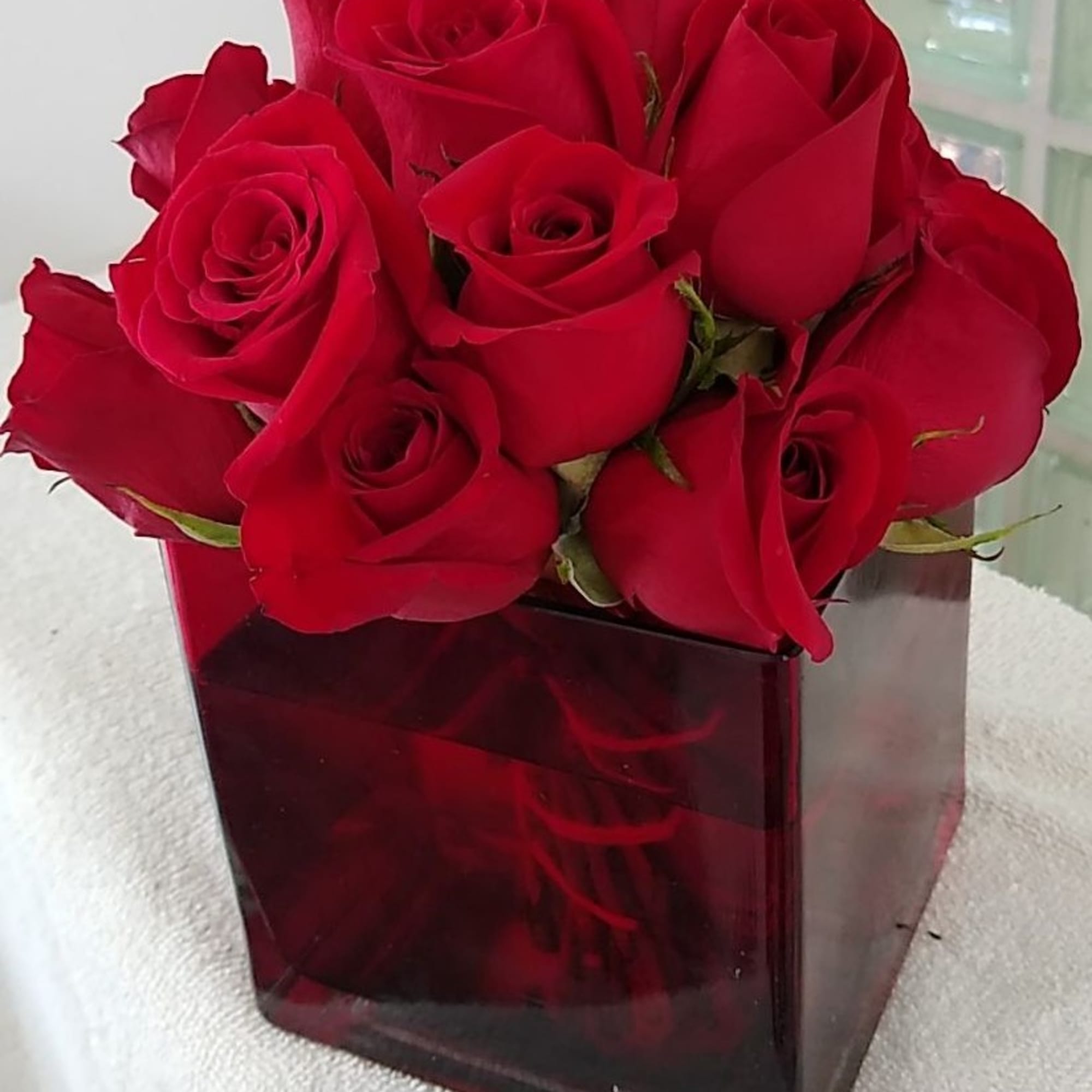 Red roses arranged in a square glass vase