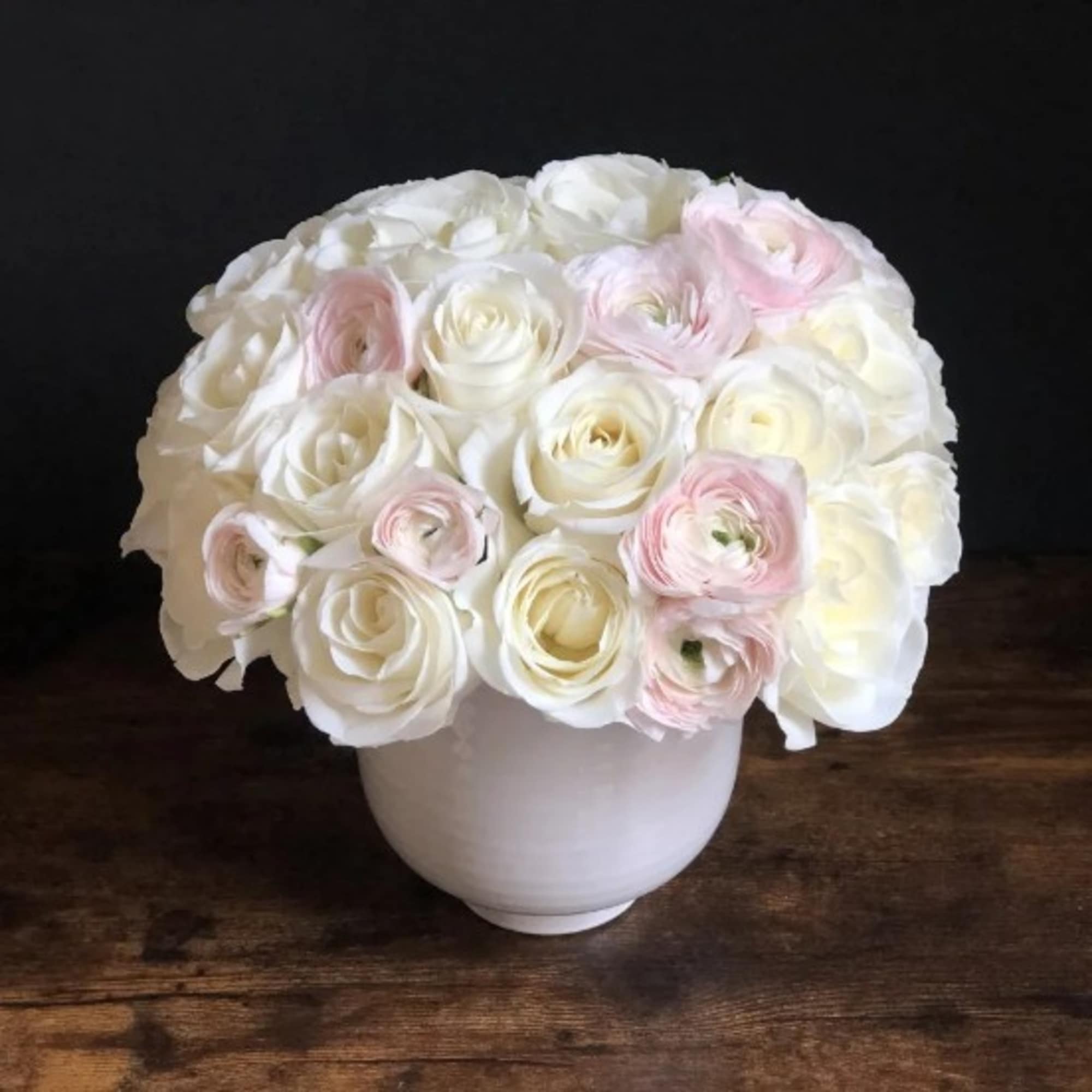 White and pale pink ranunculus in a white vase