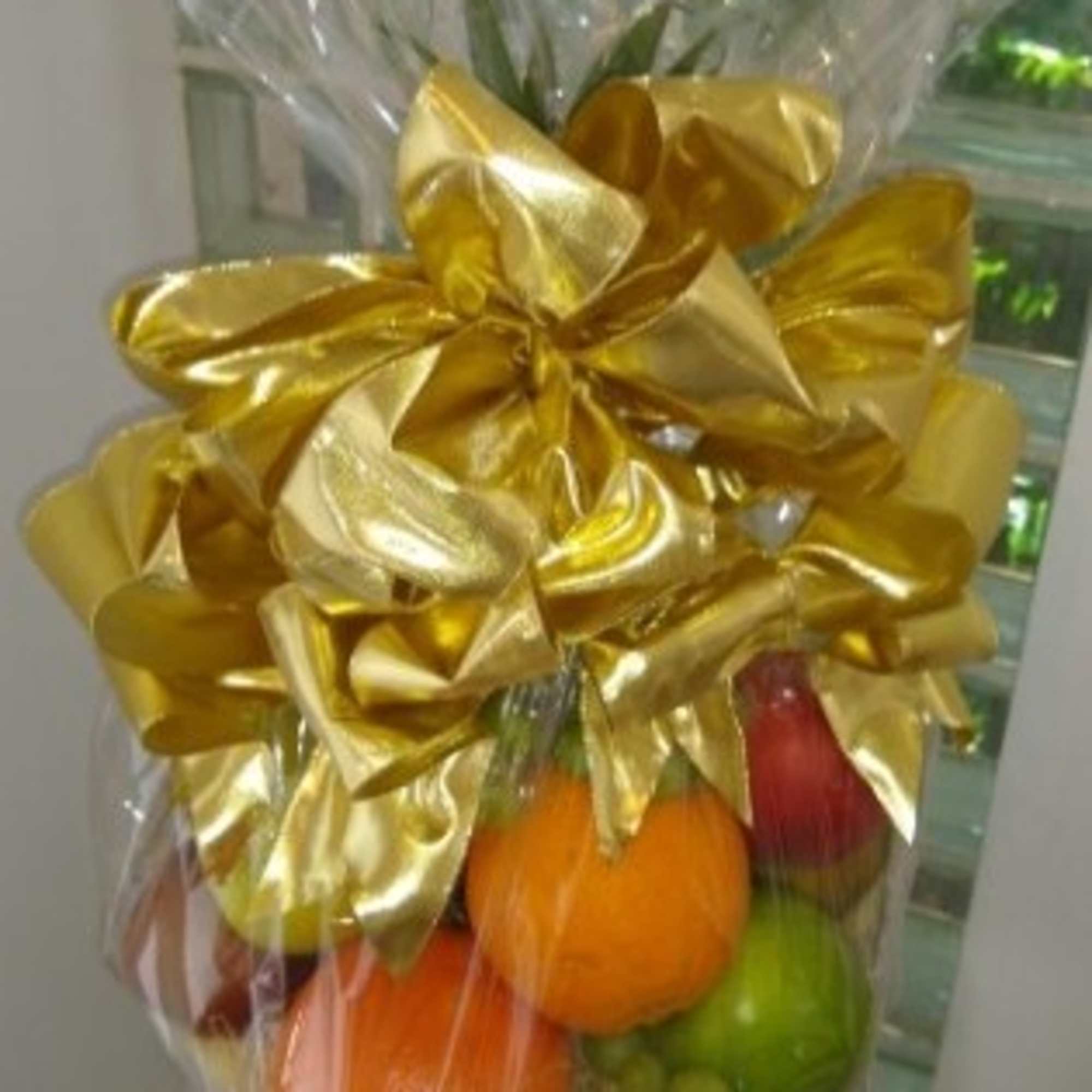Gift basket of assorted fresh fruit wrapped in cellophane with a large gold bow.