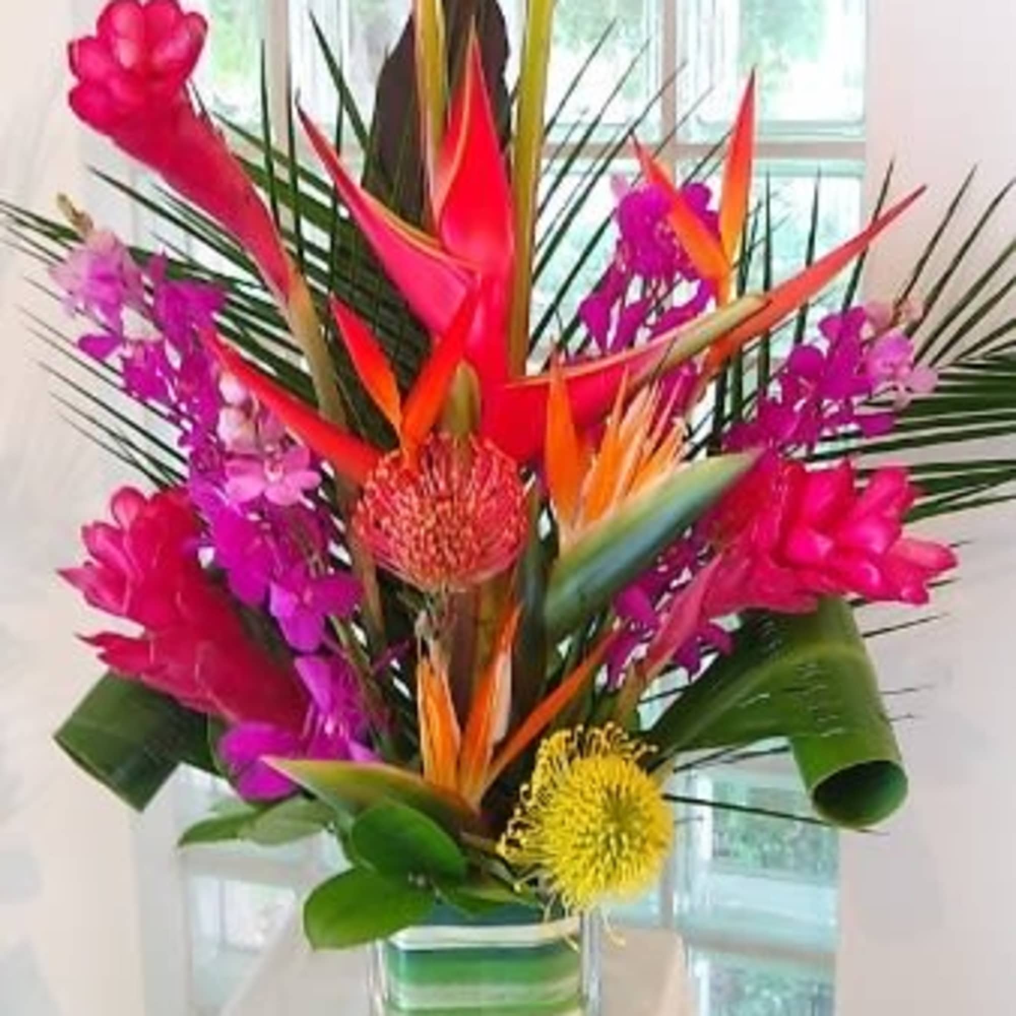 Tropical bouquet with pink and orange flowers in a glass vase